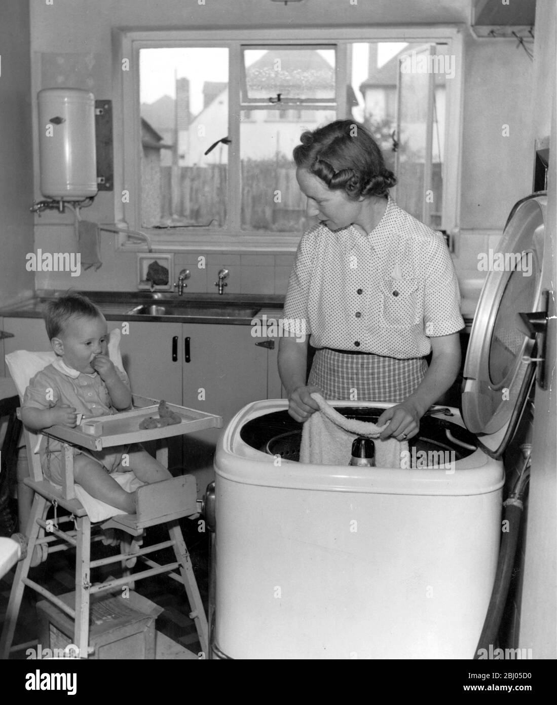 Mrs Harold Shelley and year old Peter washing the nappies in the washing machine at 8 Firgrove New Malden 1950 Stock Photo
