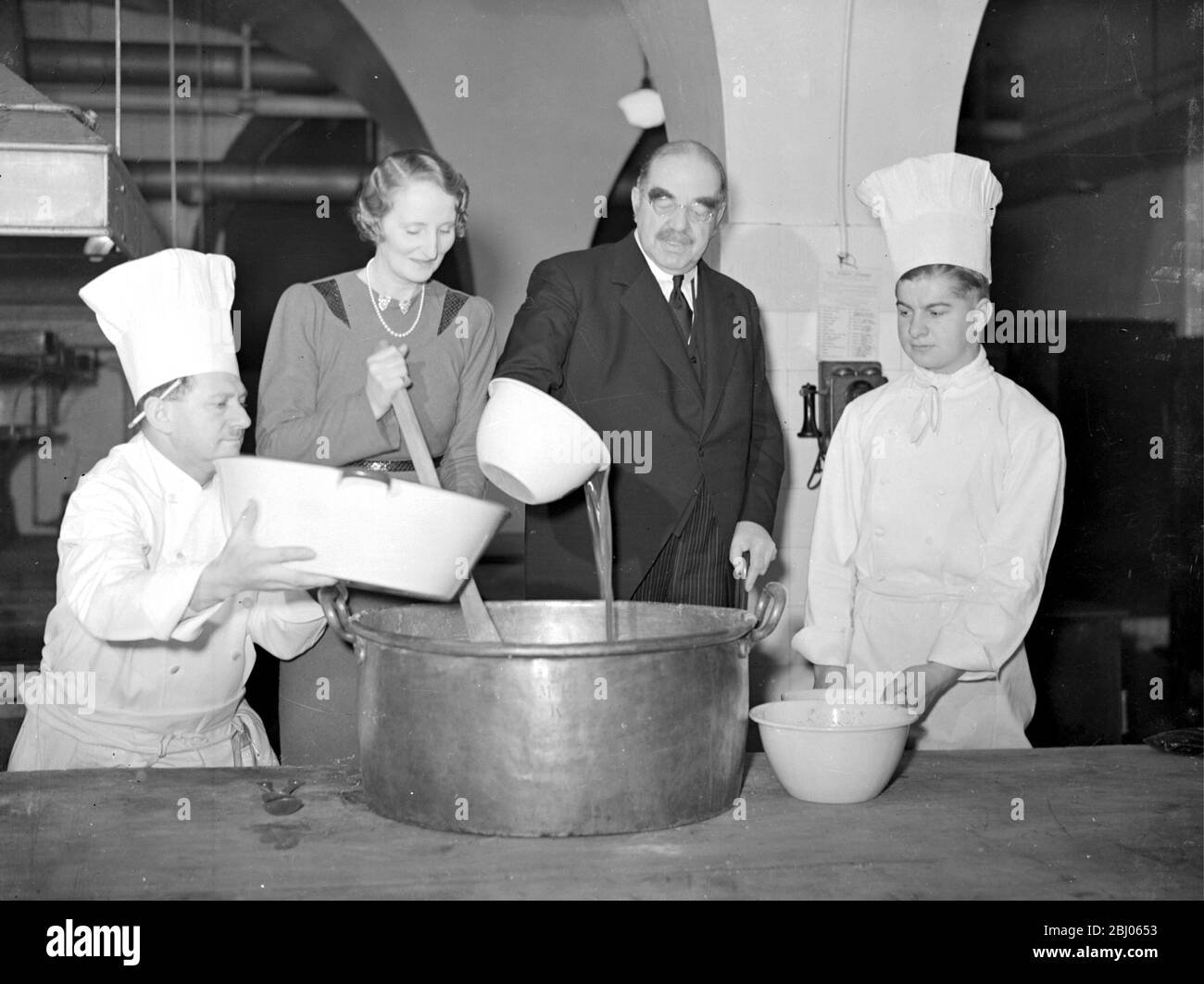 Christmas 1939 - The Lord Mayor and Lady Mayoress ( Sir William and Lady Coxen) assist The Mansion House chef, Mr E. Oyez, in the stiring and tasting of the Xmas Pudding. - 18 December 1939 Stock Photo