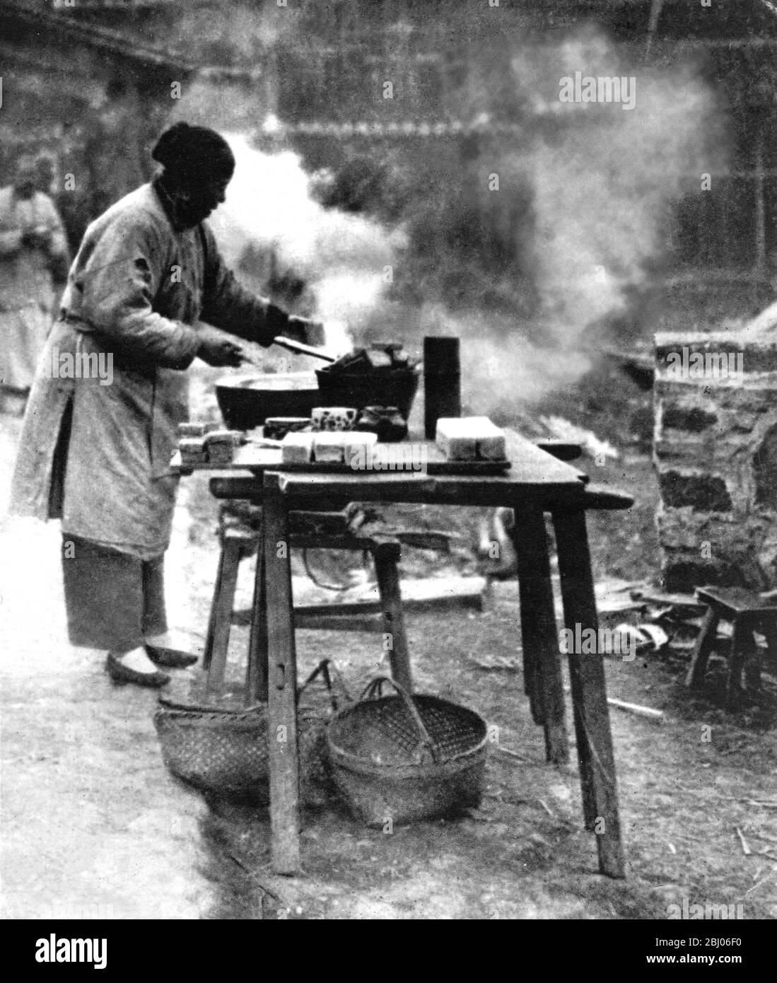 Between the Wars - China - Woman cooking in street. (Wayside restaurant) - c.1925 - Stock Photo