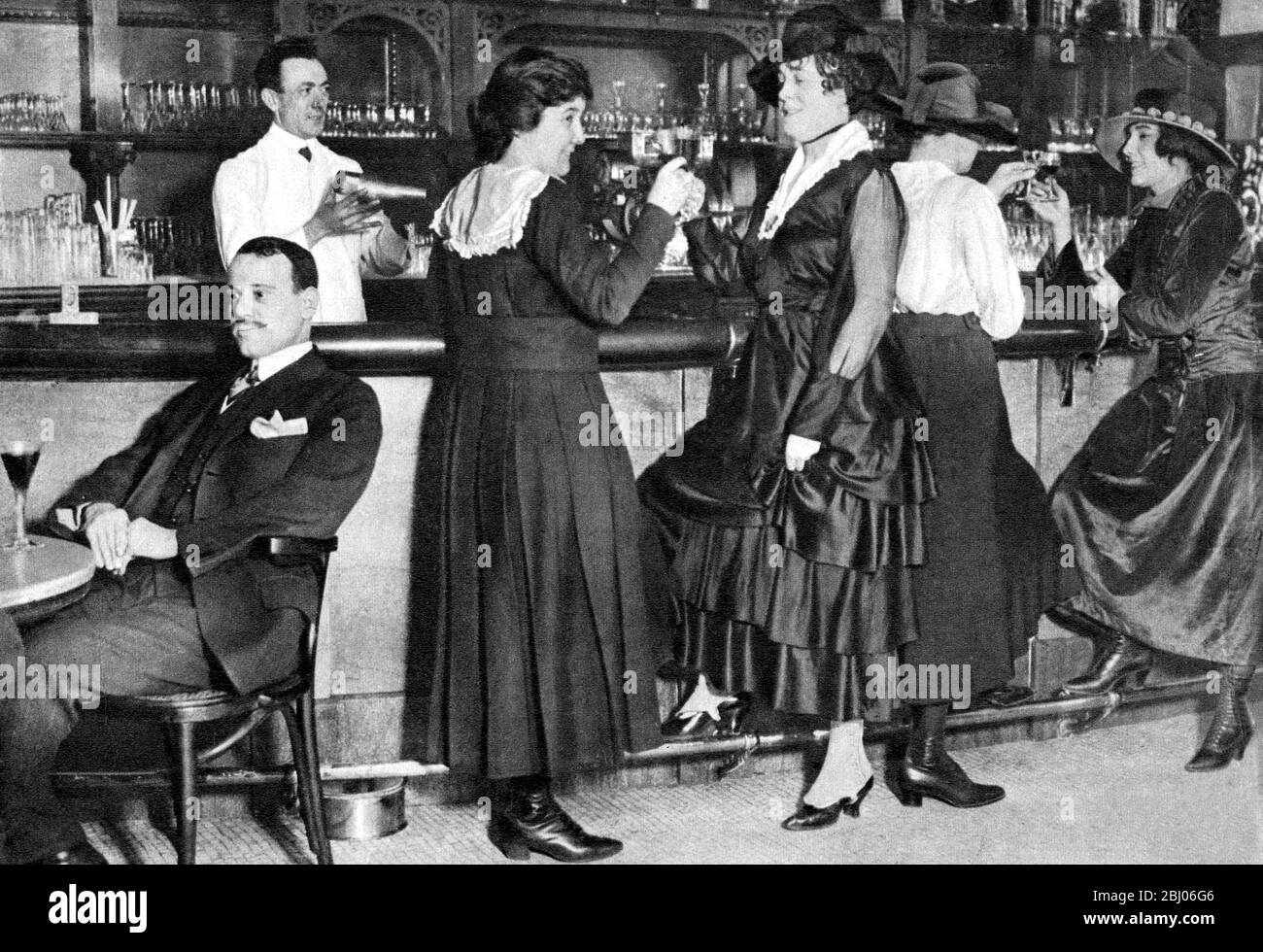 After breaking into jobs they flocked into the pubs. Feet on the bar rail and no lack of self confidence. This is the 1918 scene when one hotel admitted women to its bar, and men took a back seat. That cocktail shaker is the sign of the new age which was soon to merge into the wild twenties when women drank as much as or more that their men folk. - Stock Photo