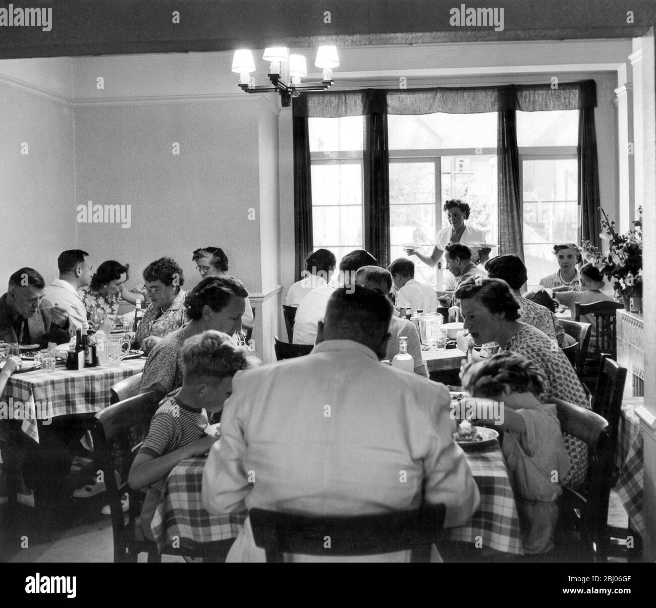 August bank holiday scramble 1953 Mr and Mrs Smiths boarding house Margate - Holiday makers sit down to a meal. Stock Photo