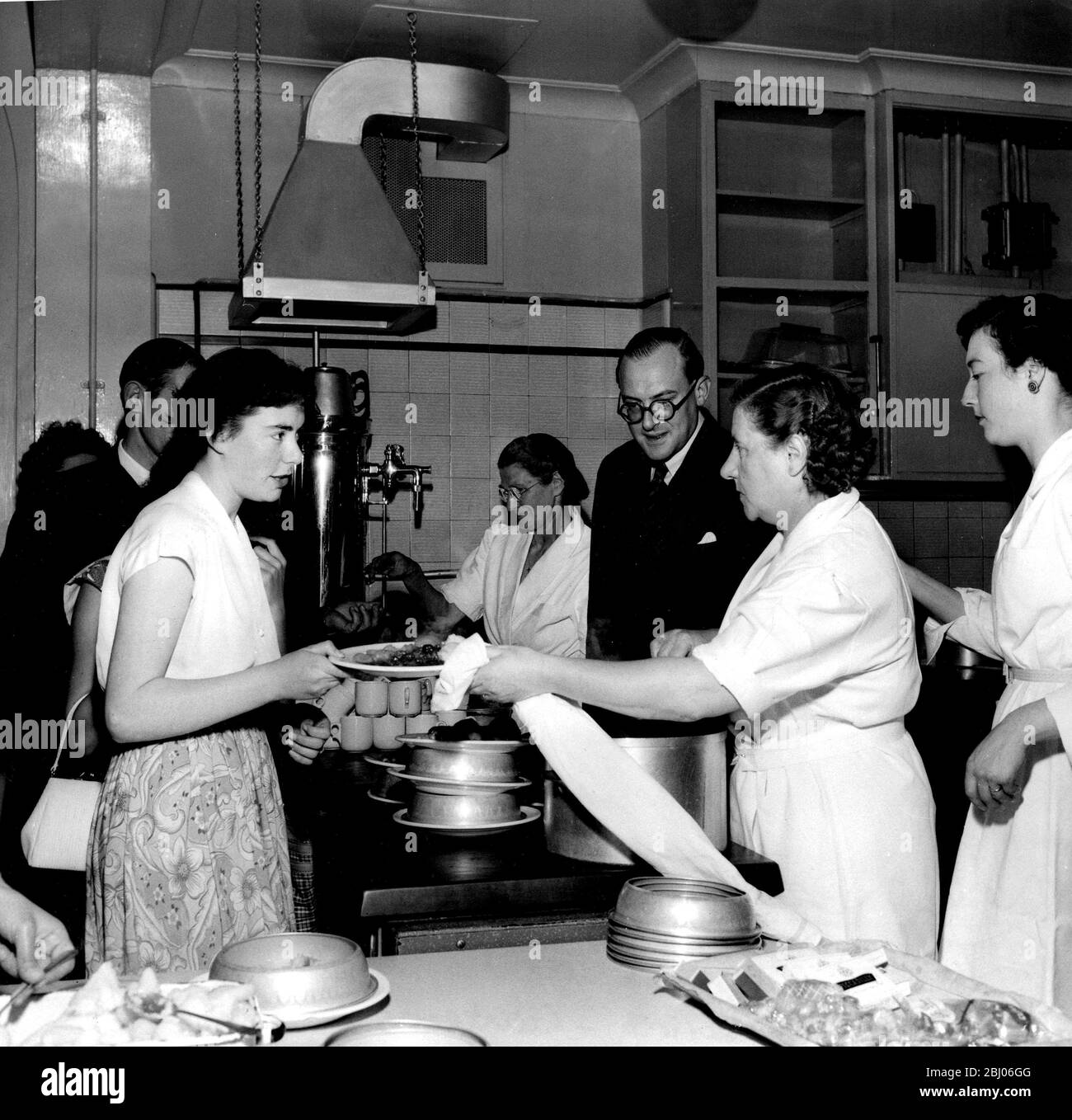 Nigel Radcliffe tours the world perfect kitchens and installs everything from a complete kitchen to a grill capable of cooking a steak in sixty seconds. He is seen here watching serving staff at a canteen in London where his equipment is in use. - 1954 Stock Photo