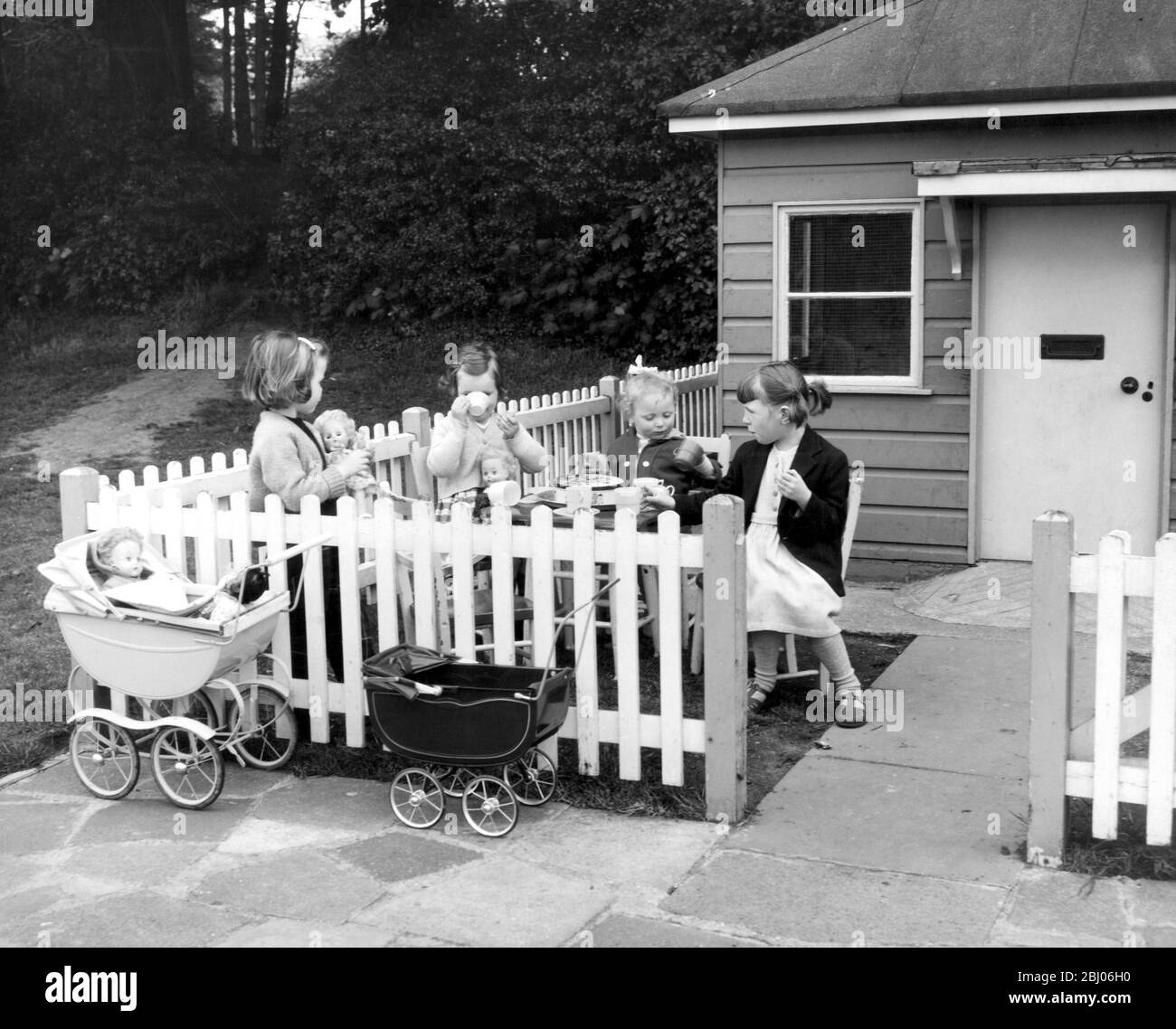 (L to R) Caryl Hastings, aged 5 Sally Hastins, aged 3, Sarah Hook, aged 2, Lynne Whitehead, aged 4, enjoying an afternoon tea party at the Wendy House in the Totteridge Park Recreation Ground, North London. - 5 June 1962 Stock Photo