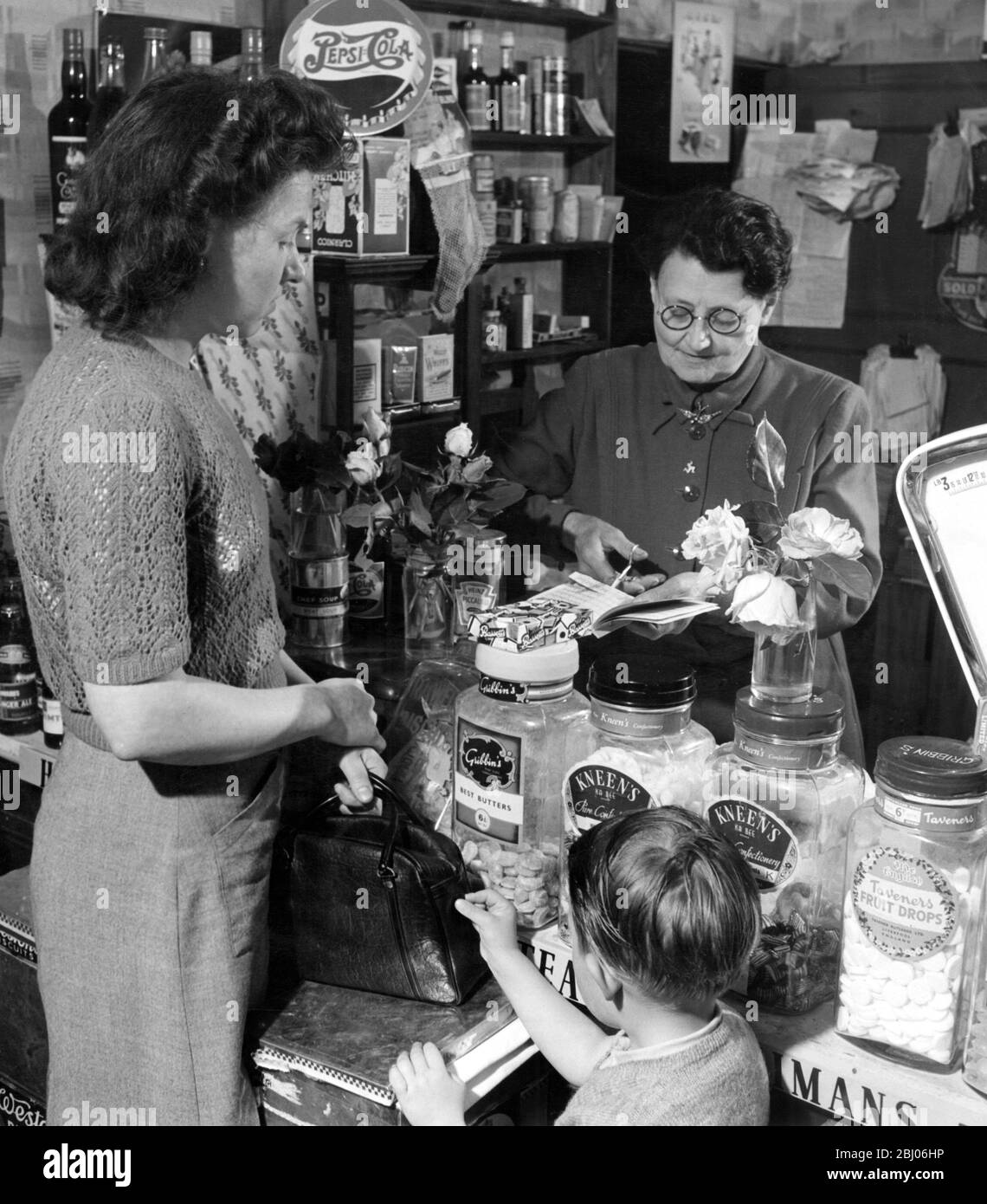 Mrs Alice Qualtrough who keeps the village store at St John's cutting out the ration book of one of her customers. - Undated. - Stock Photo