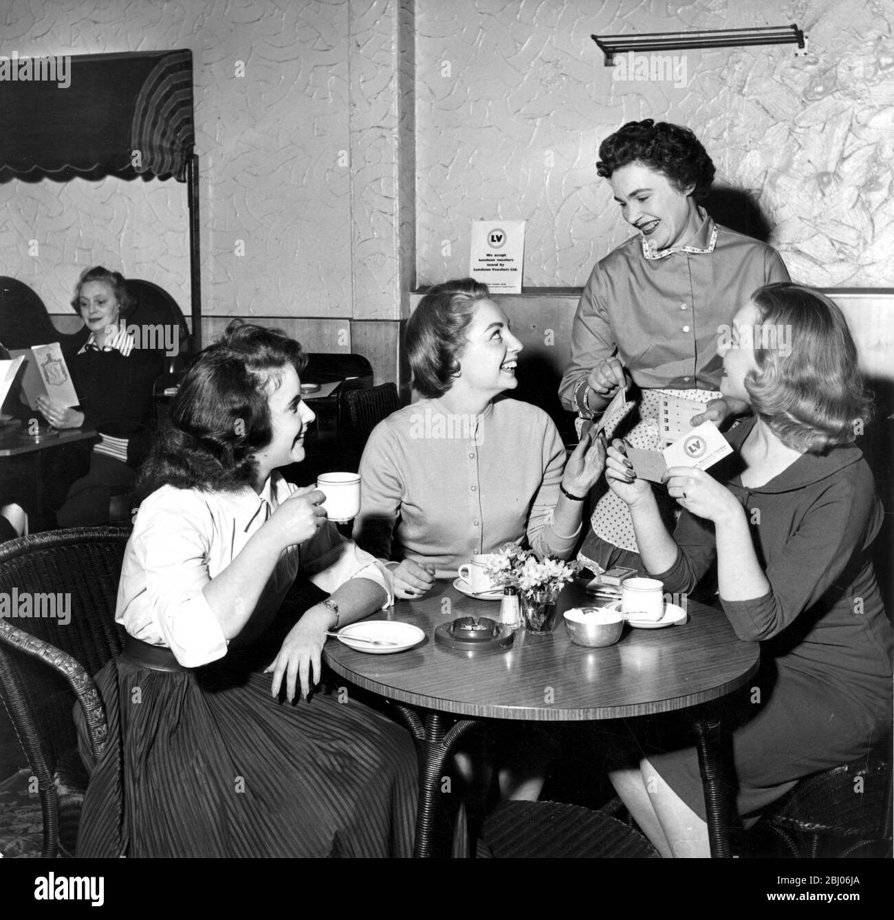 Vouchers encourage workers to eat lunch regularly, without skimping it. One doctor found that his office staff spent lunch money on records and nylons - picture shows after lunch at the S & R grill in Denman Street - girls pay for their meal with luncheon vouchers. 1957 Stock Photo