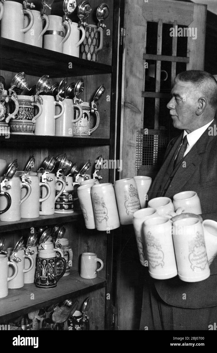 Regular customers of a beer cellar in Austria have their own beer jugs. The waiter at Saltzburg Beer cellar in front of the cupboard containing the regulars' special jugs Stock Photo