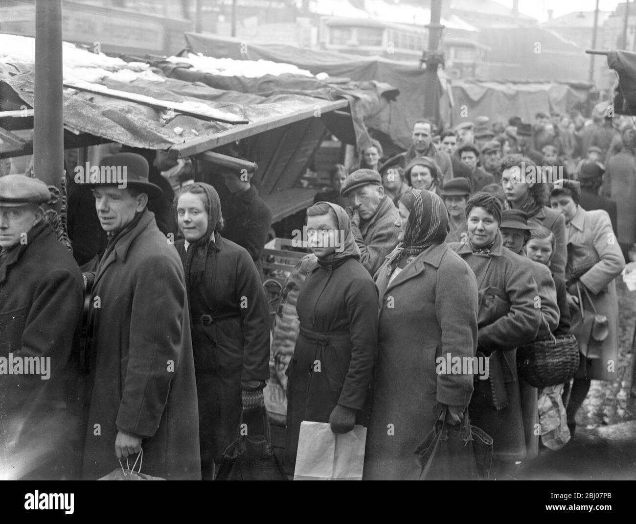 The weather brings a shortage of potatoes . The supplies of potatotes have been seriously menaced by the weather, owing to farmers being unable to open up clamps . A queue for potatoes seen at Beresford Square , Woolwich - 8 March 1947 Stock Photo