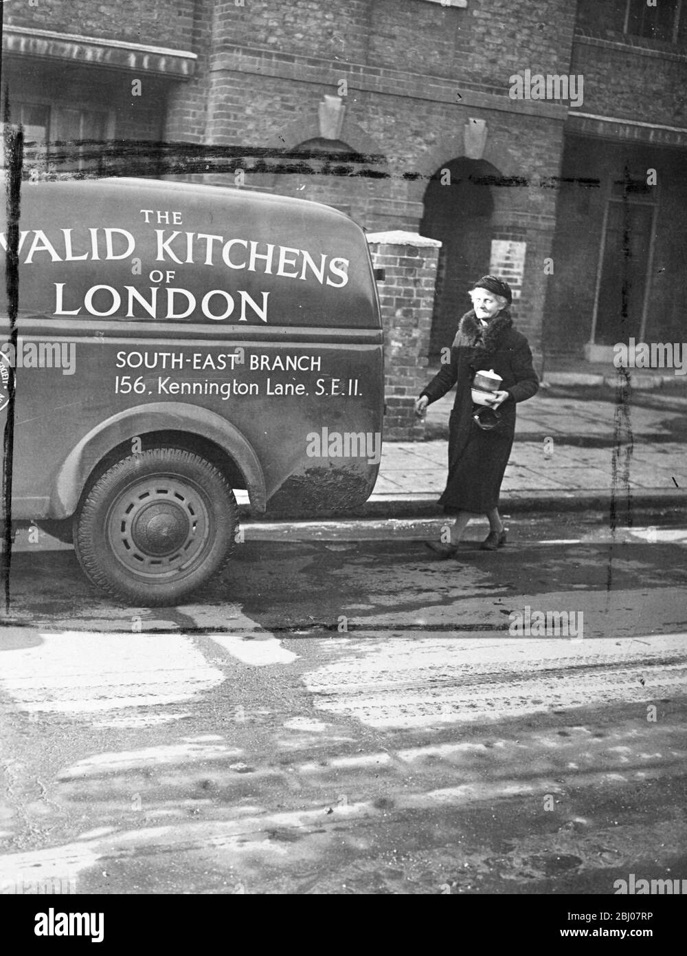 Feeding the infirm during the ice blitz. - The invalid kitchens of London, have been kept busy during the recent 'freezer', delivering dinners to infirm people. Run by voluntary contributions, the kitchens deliver an average of 60 dinners daily to London's invalids unable to leave their homes. - Photo shows, Mrs Ewins at work in London, delivering cans of food to a home of an invalid. - 26 February 1947 Stock Photo