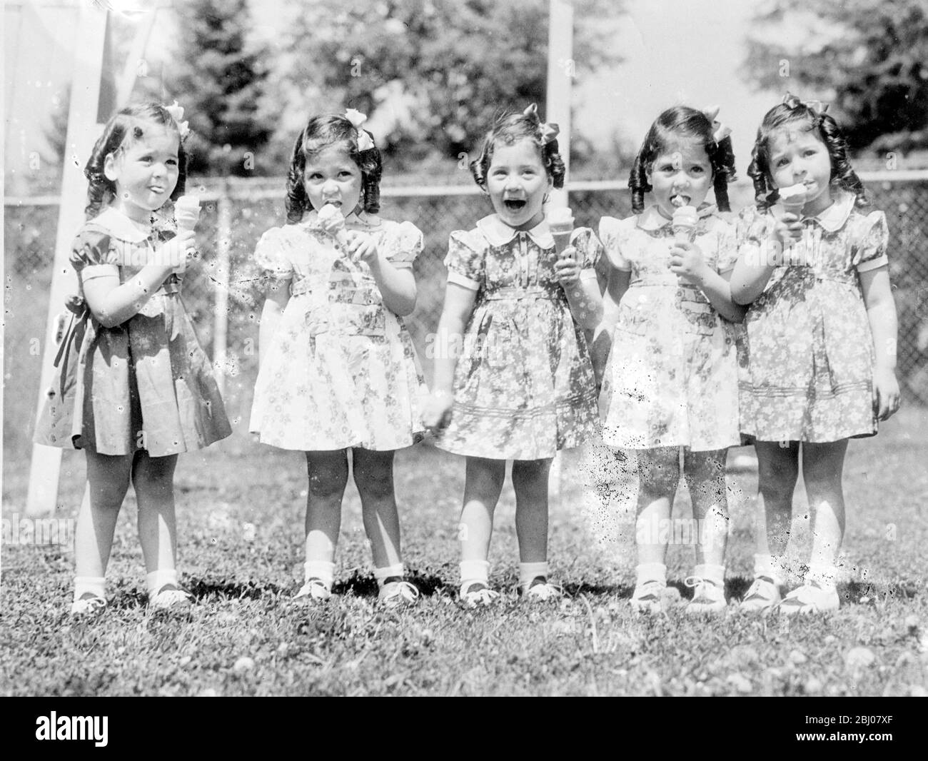 Quins are allowed ice cream now. - the Dioone quintuplets with busy tounges and smiling faces, demonstrate their liking for ice cream, a novelty for them at their Callander, Ontario, nursery. - The five girls, Emilie, Annette, Marie, Cecile and Yvonne, were allowed ice cream for the first timeat their fourth birthday. - 5 July 1938 Stock Photo