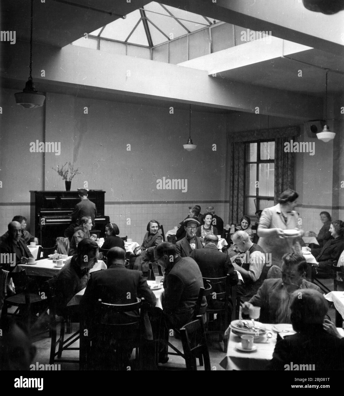 The canteen at the Vine Cotton Mill in Royton, Greater Manchester, England - The table cloths and curtains are all made from cotton spun at the mill. Workers can get a three course meal for a shilling and anyone is welcome to play the piano which is rarely unoccupied. - 26 March 1946 - Stock Photo