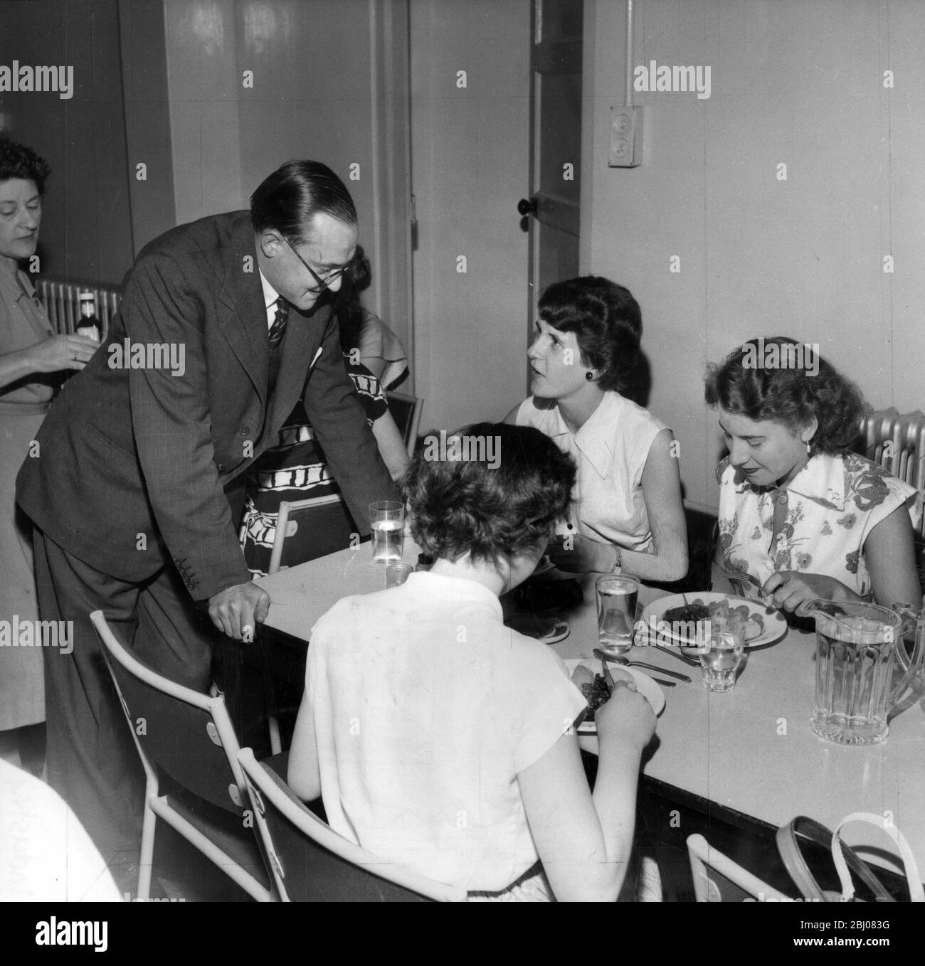 Nigel Radcliffe tours the world fitting perfect kitchens. Here he is seen chatting to office girls about the staff canteen. - London, England - 11 September 1954 - Stock Photo
