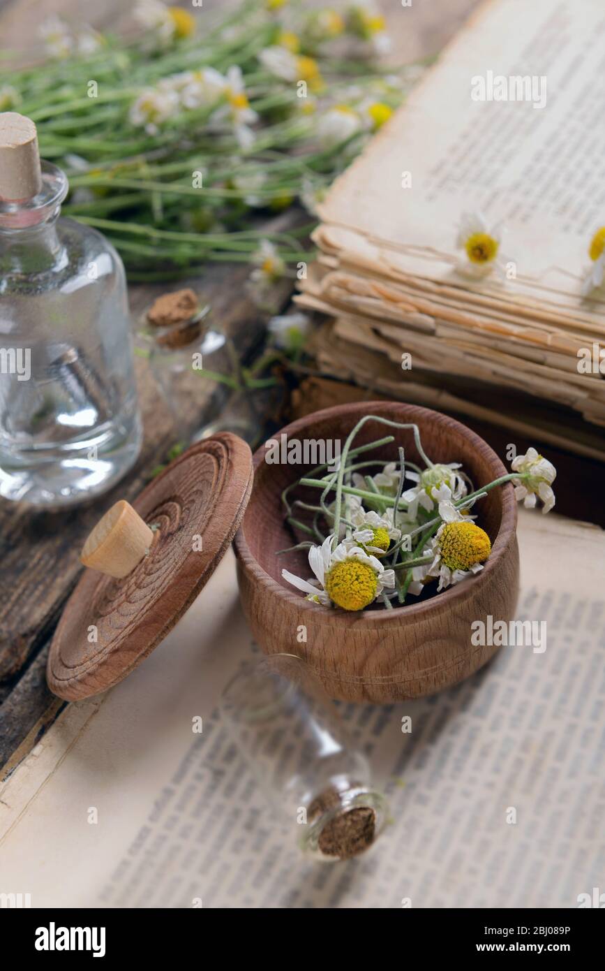 Old book with dry flowers in mortar on table close up Stock Photo