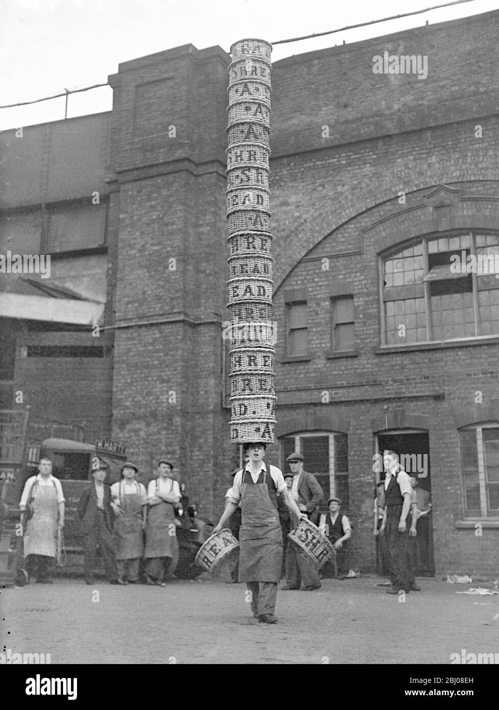 Alf Hardy, aged 17, carrying 18 baskets on his head and one in each hand at Borough Market. Alf, a junior porter at the market, is out to win the first prize of å£20 presented by Charlie Chaplin to the winner of All-England half-bushel basket championship of the Borough Market Athletic Association's sports at Herne Hill on September 9. This is the seventh successive year in which Charlie Chaplin has given the first prize.31 August 1937 Stock Photo