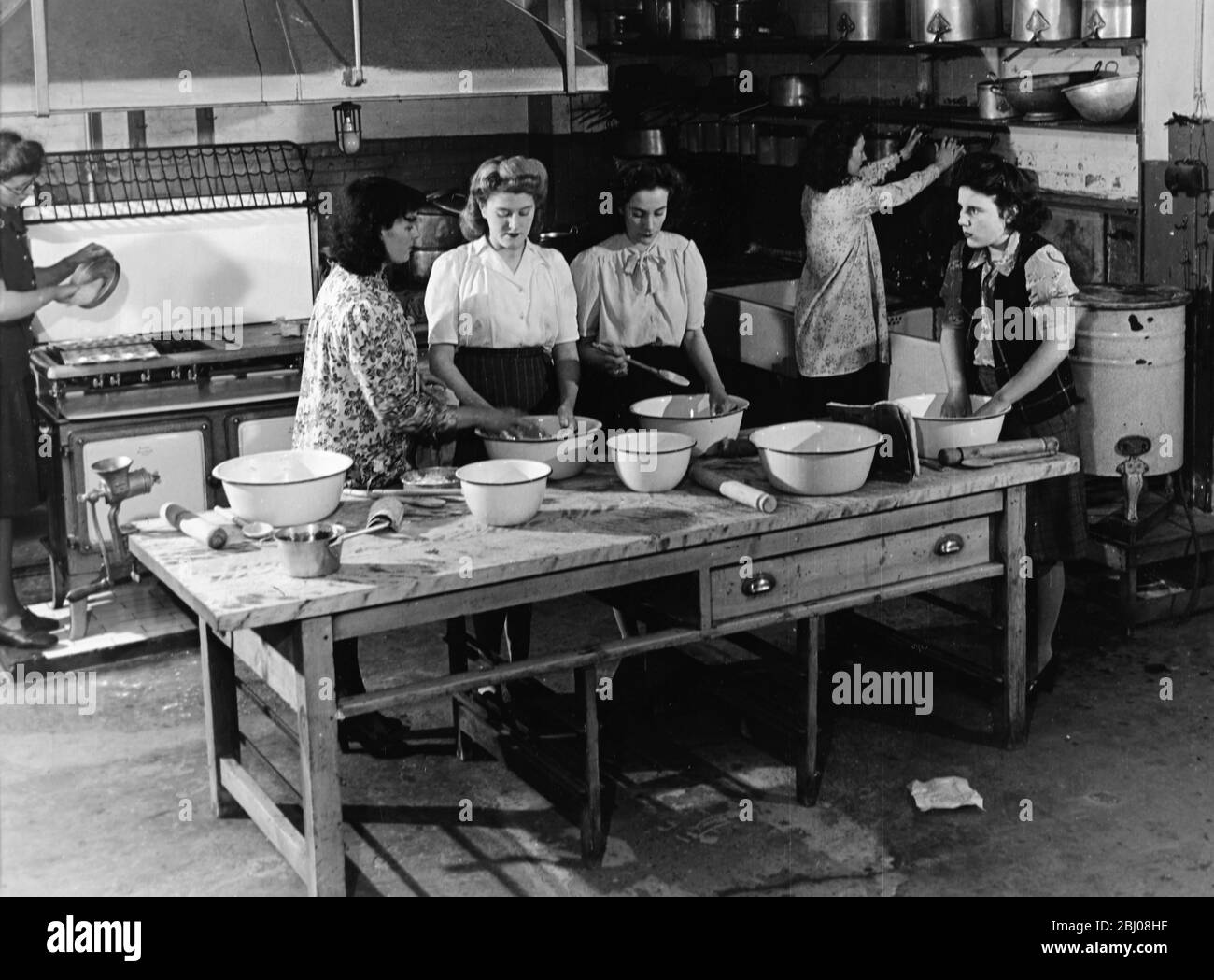 Teaching young women cooking in a kitchen - 1950s Stock Photo