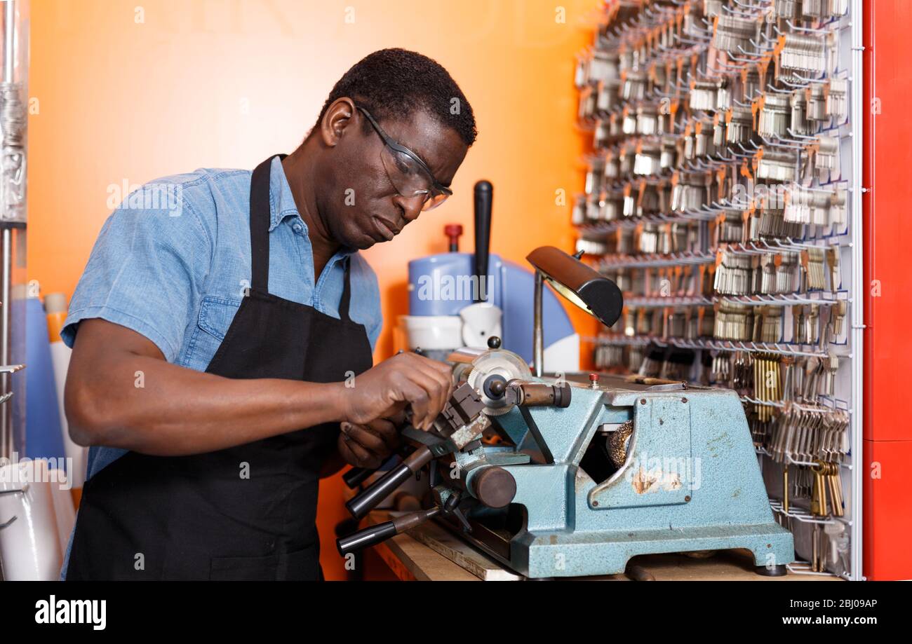 Professional serious skilled key cutter making duplicates of door keys in locksmith shop Stock Photo