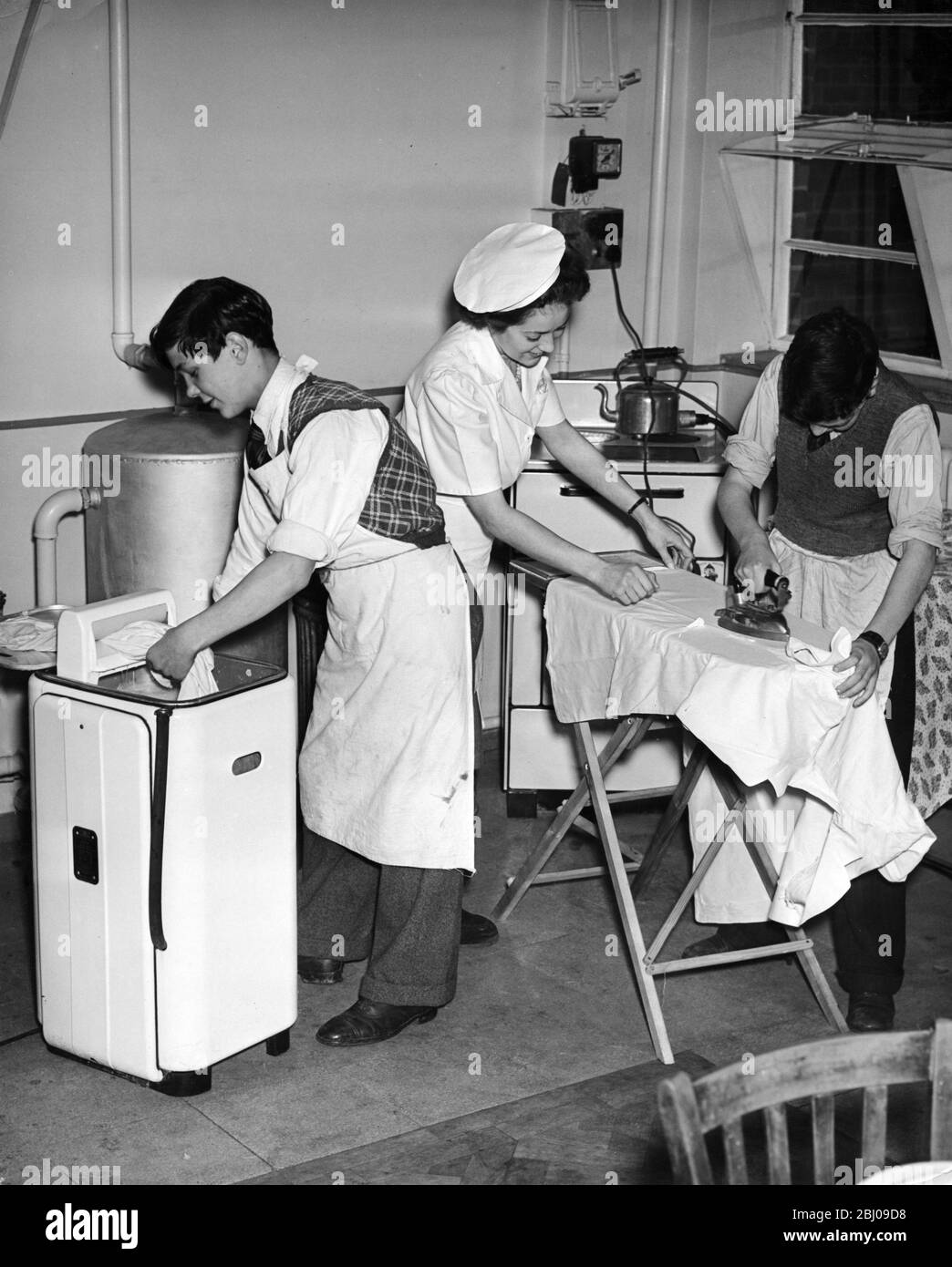 At Arnos Secondary Modern School , Southgate , the pupils reverse the usual order of things during their Friday afternoon handicraft ande domestic science sessions . The boys do cookery and needlework and the girls work in metal and wood . -  Laundry lads ; two of the boys find that doing the washing can be fun . Left to right John Pettit of Muswell Hill (14 ) ; Instructress , Mrs K Armitage of Palmers Green ; and John Baily , 15 of Southgate - 22nd November 1950 Stock Photo