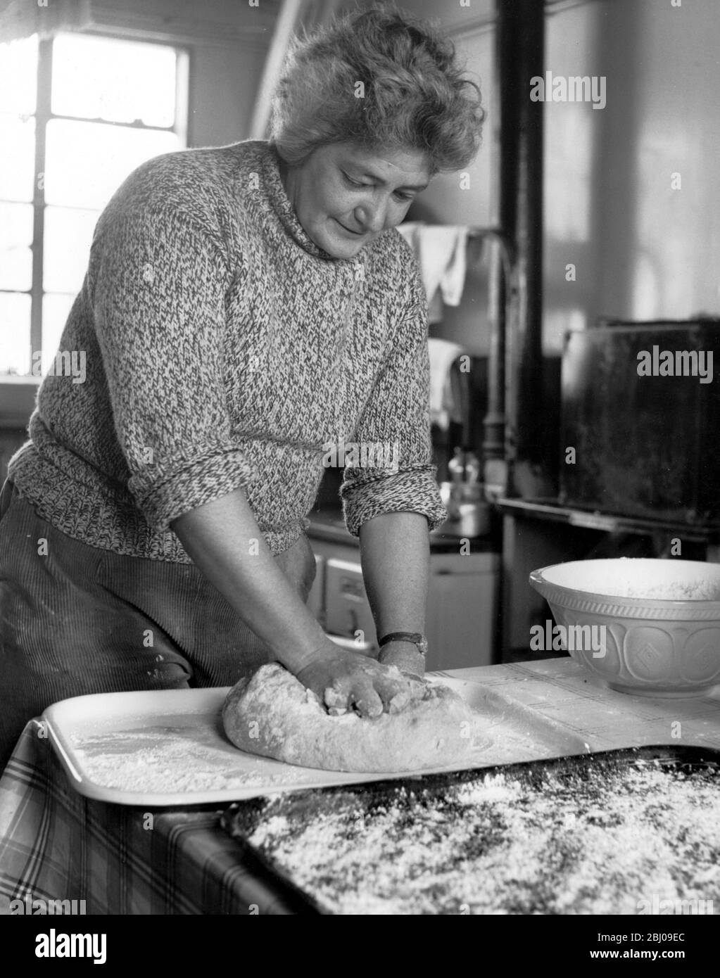 Britains Loneliest Island Employed by the Observatory Trust for staff and visitors Pat has to do the cooking in this picture is baking anbd preparing bread 22 July 1957 Stock Photo
