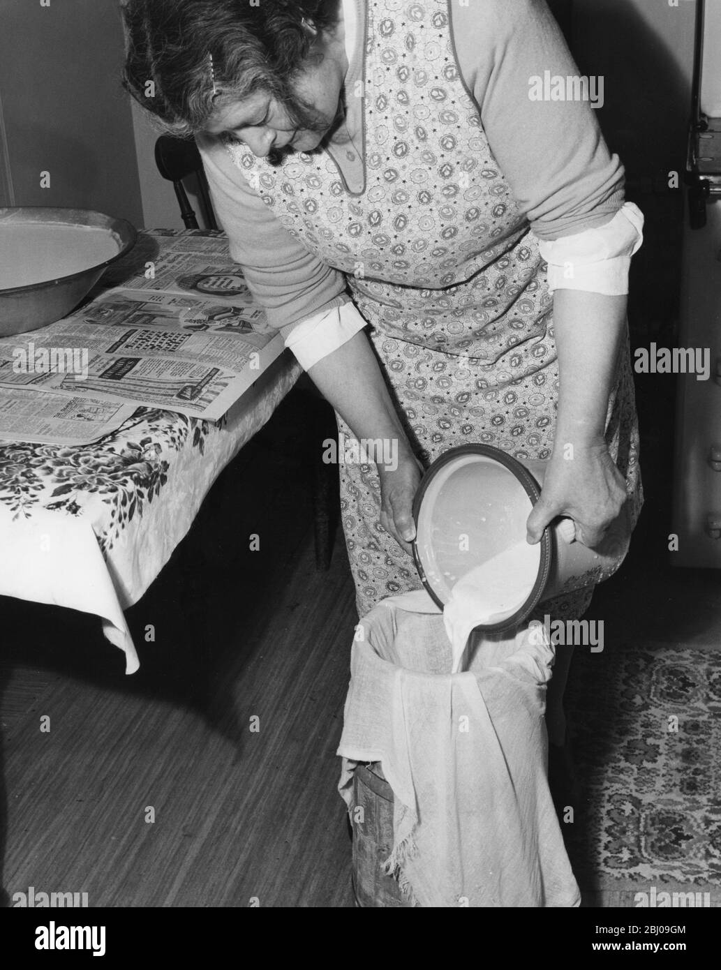 Miss Peggy Macleod making butter pouring the milk through muslin into a churn in Daliburgh South Uist Outer Hebridges Scotland - September 1961 Stock Photo