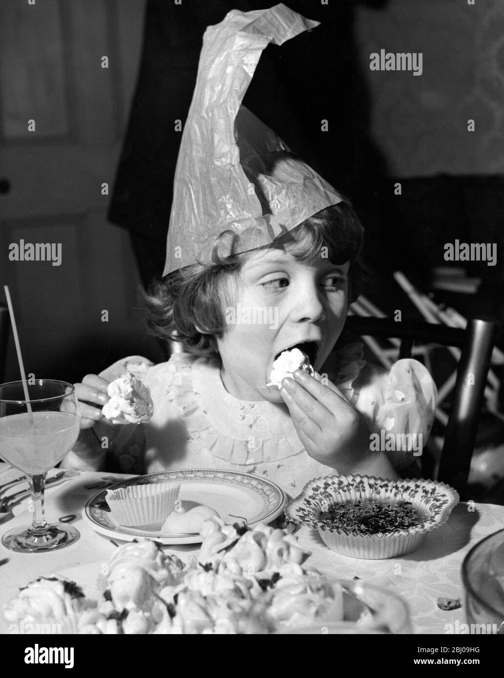 Della Anphlett , age 6 , eats a cup cake at the Variety Club Christmas Party for children at St. Agnes Orphanage, Thames Ditton. - 15 Ennismore Gardens, London SW7, England - 19 December 1959 Stock Photo