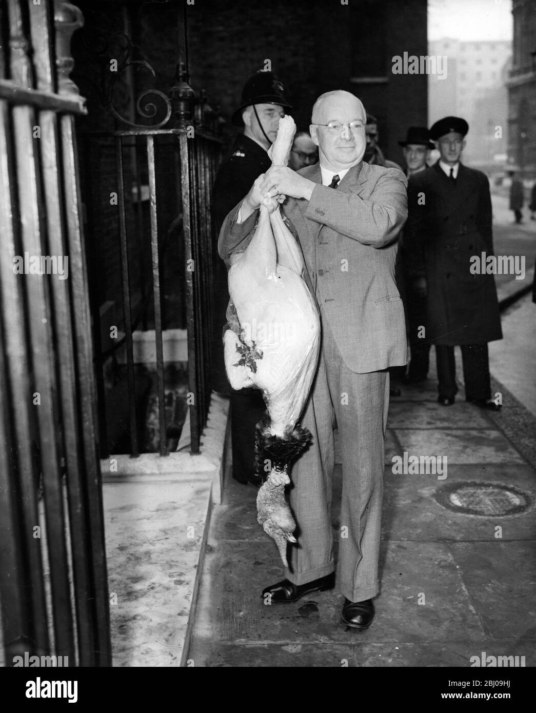 Colonel A.M. Melville , Vice President of the British Turkey Federation , holds up a 40 lbs turkey as a gift to Prime Minister Sir Winston Churchill - 10 Downing Street, London, England - 22 December 1953 Stock Photo
