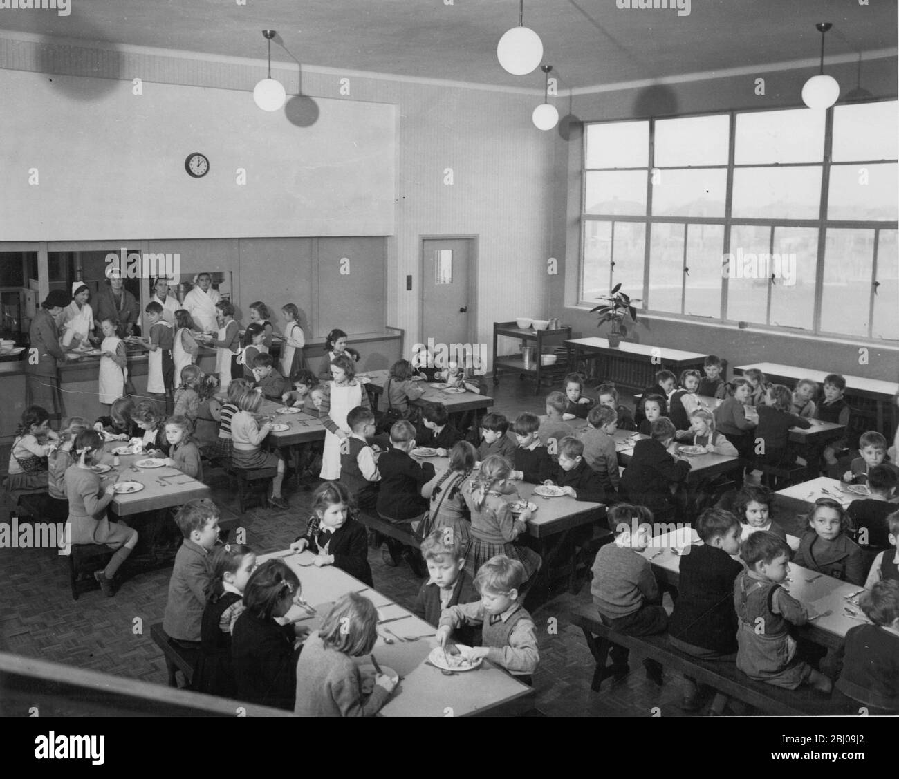 Lunchtime at school , children line up patiently with thier trays to get their meals from the dinner ladies . - 4 February 1952 Stock Photo