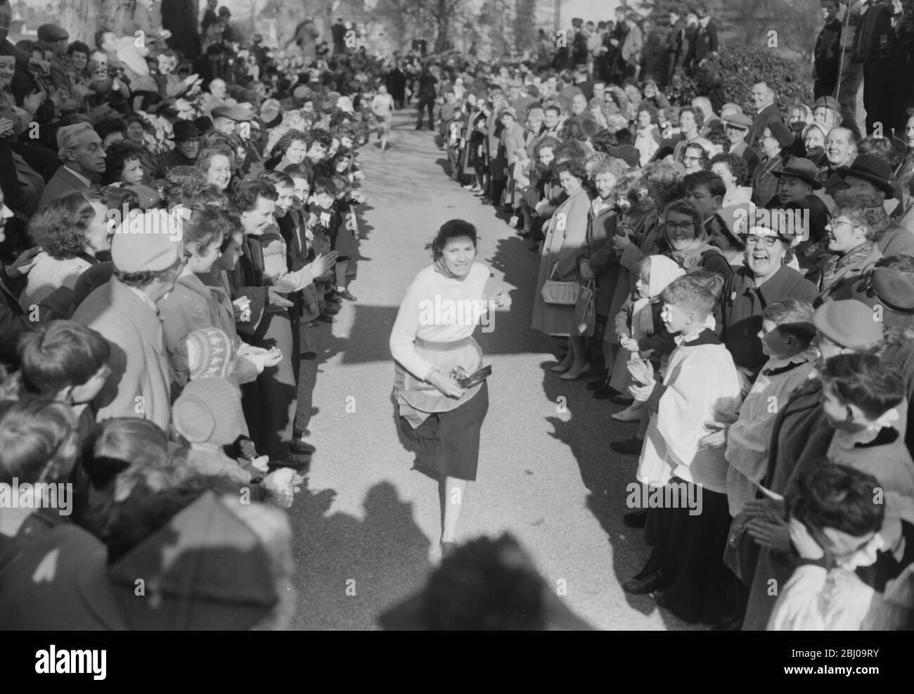 14 FEBRUARY 1961 - CAROL VORLEY - 19 YEAR OLD WINNER OF THE OLNEY PANCAKE RACE AT THE FINISHING LINE AFTER COMPLETING THE 415 YARD COURSE IN 1 MINUTE AND 14 SECONDS. THE RACE DATES BACK TO 1445 AND WAS REVIVED BY THE LOCAL VICAR IN 1946. - OLNEY, BUCKINGHAMSHIRE, ENGLAND Stock Photo