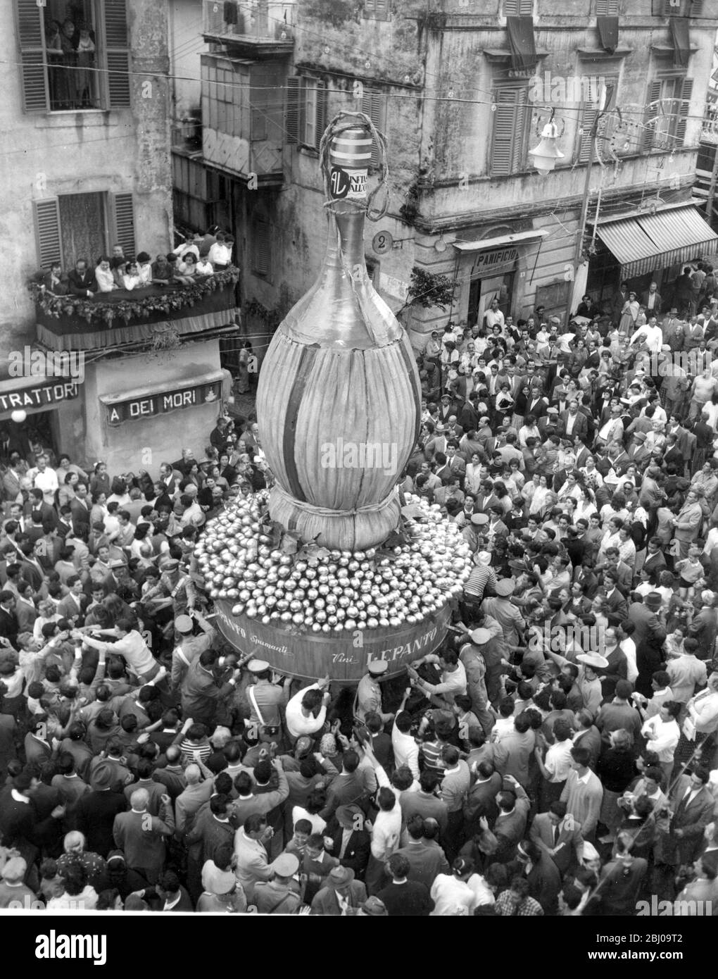 Marino , Italy . - Towns yearly wine festival celebrated on the first sunday of October . - Huge flask placed on the water fountain in the centre of square and wine is distributed free to the gathered crowd . - October 1958 - - Stock Photo
