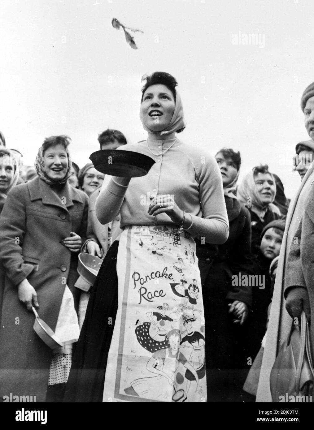 1 MARCH 1960 - CAROL VORLEY - 18 YEAR OLD WINNER OF THE OLNEY PANCAKE RACE FLIPS A PANCAKE AT THE FINISHING LINE AFTER COMPLETING THE 415 YARD COURSE IN 1 MINUTE AND 10 SECONDS. THE RACE DATES BACK TO 1445 AND WAS REVIVED BY THE LOCAL VICAR IN 1946. - OLNEY, BUCKINGHAMSHIRE, ENGLAND Stock Photo