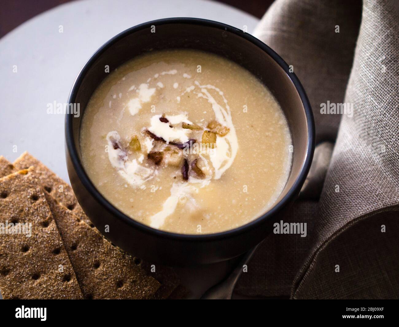 Celeriac and blue cheese soup with garnish of fried pancetta and apples Stock Photo