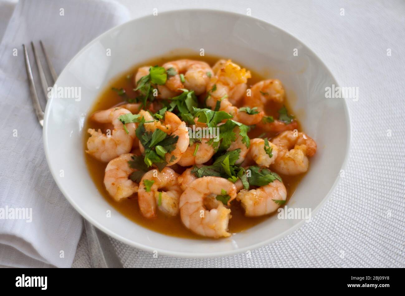 Simple dish of large prawns stir fried with garlic, and Thai sweet chilli dipping sauce sprinkled with coriander Stock Photo