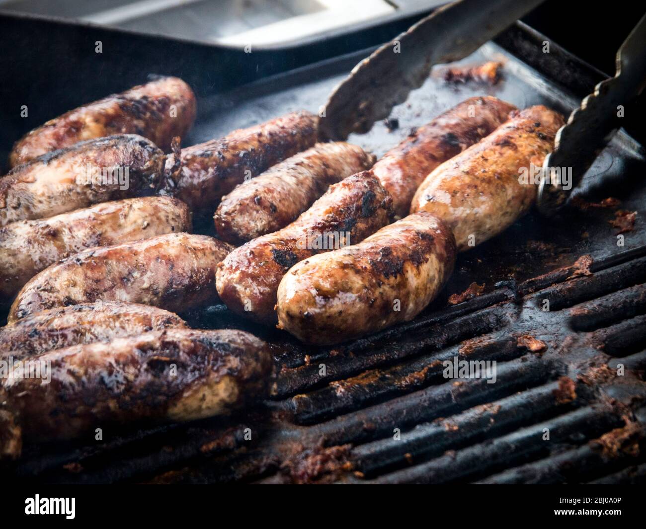 Free range pork sausages being grilled at Penshurst farmers 'market Stock Photo
