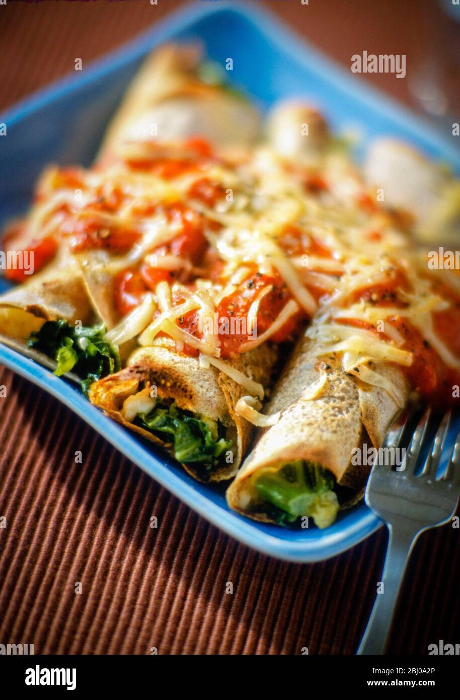 Buckwheat pancakes stuffed with vegetables and baked with tomato sauce and cheese Stock Photo