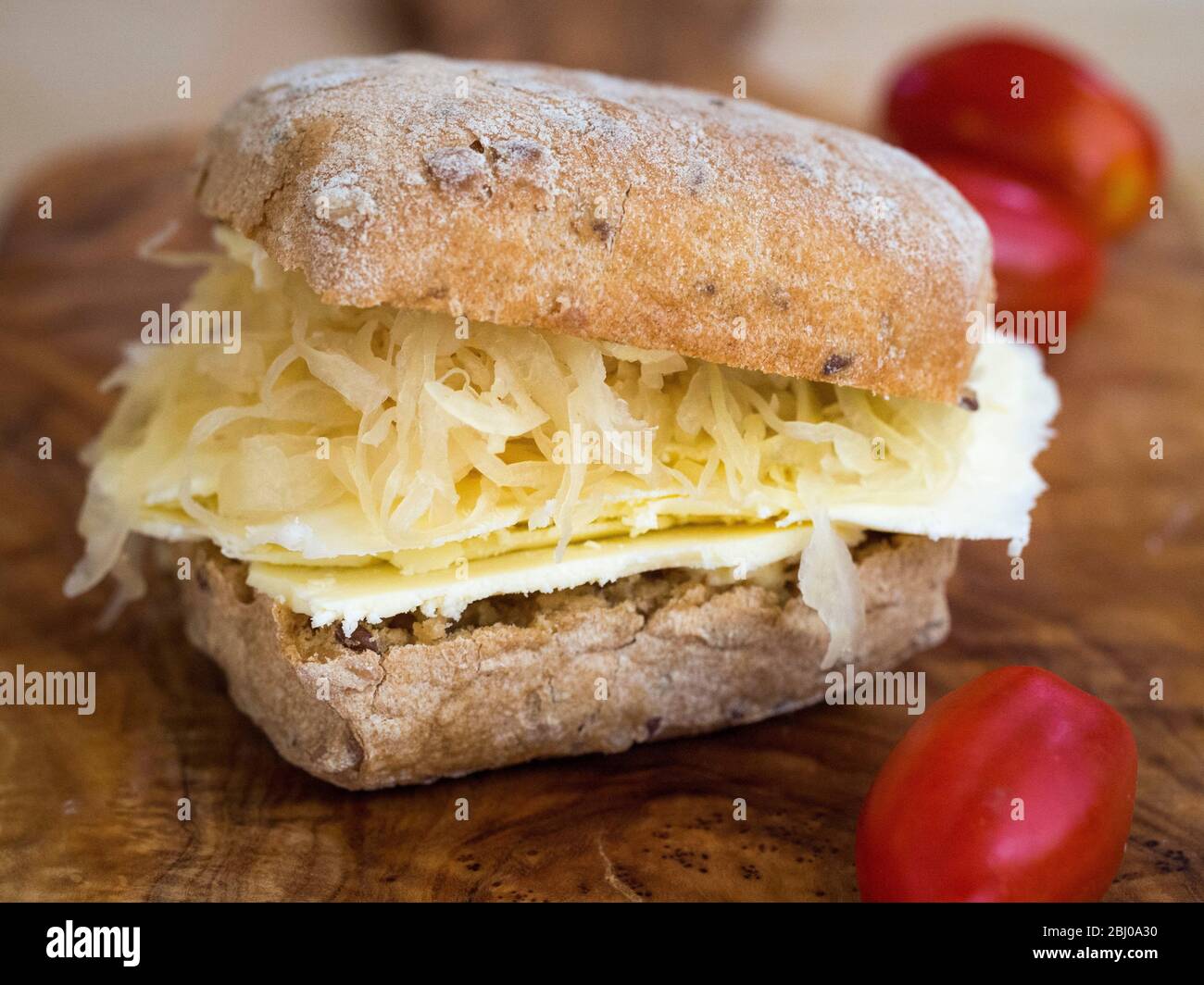 Nourishing lunchtime sandwich of thinly sliced Cheshire cheese with sauerkraut on brown seeded ciabatta. (Gluten free bread) Stock Photo