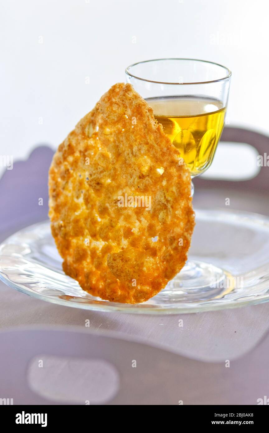 Tuile biscuit with small glass of dessert wine on glass plate - Stock Photo
