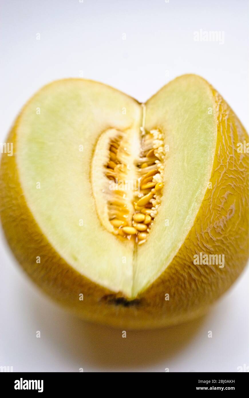 Cut face of galia melon showing flesh and seeds in interior - Stock Photo
