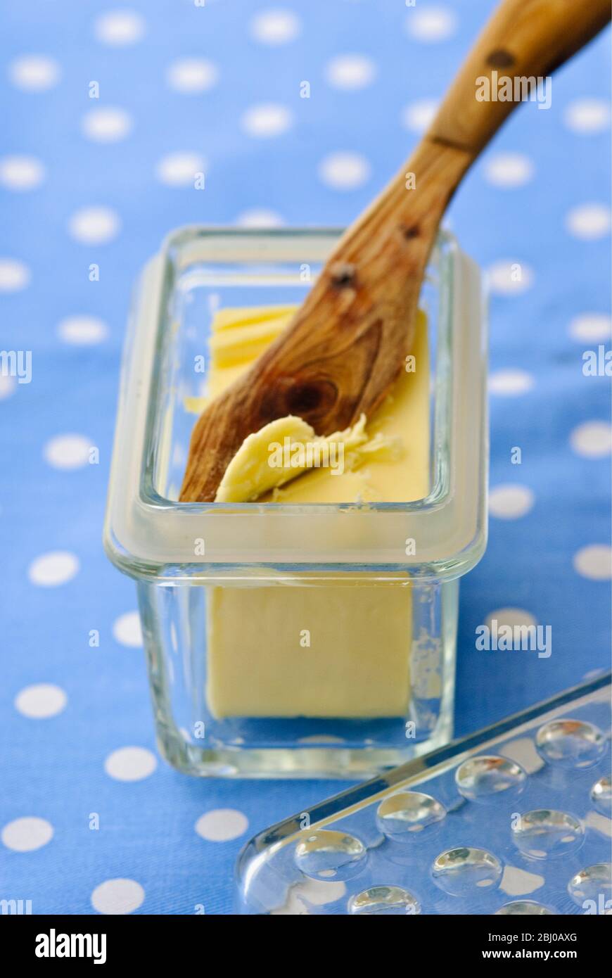 https://c8.alamy.com/comp/2BJ0AXG/glass-butter-dish-of-butter-with-butter-knife-on-blue-and-white-spotted-cloth-2BJ0AXG.jpg