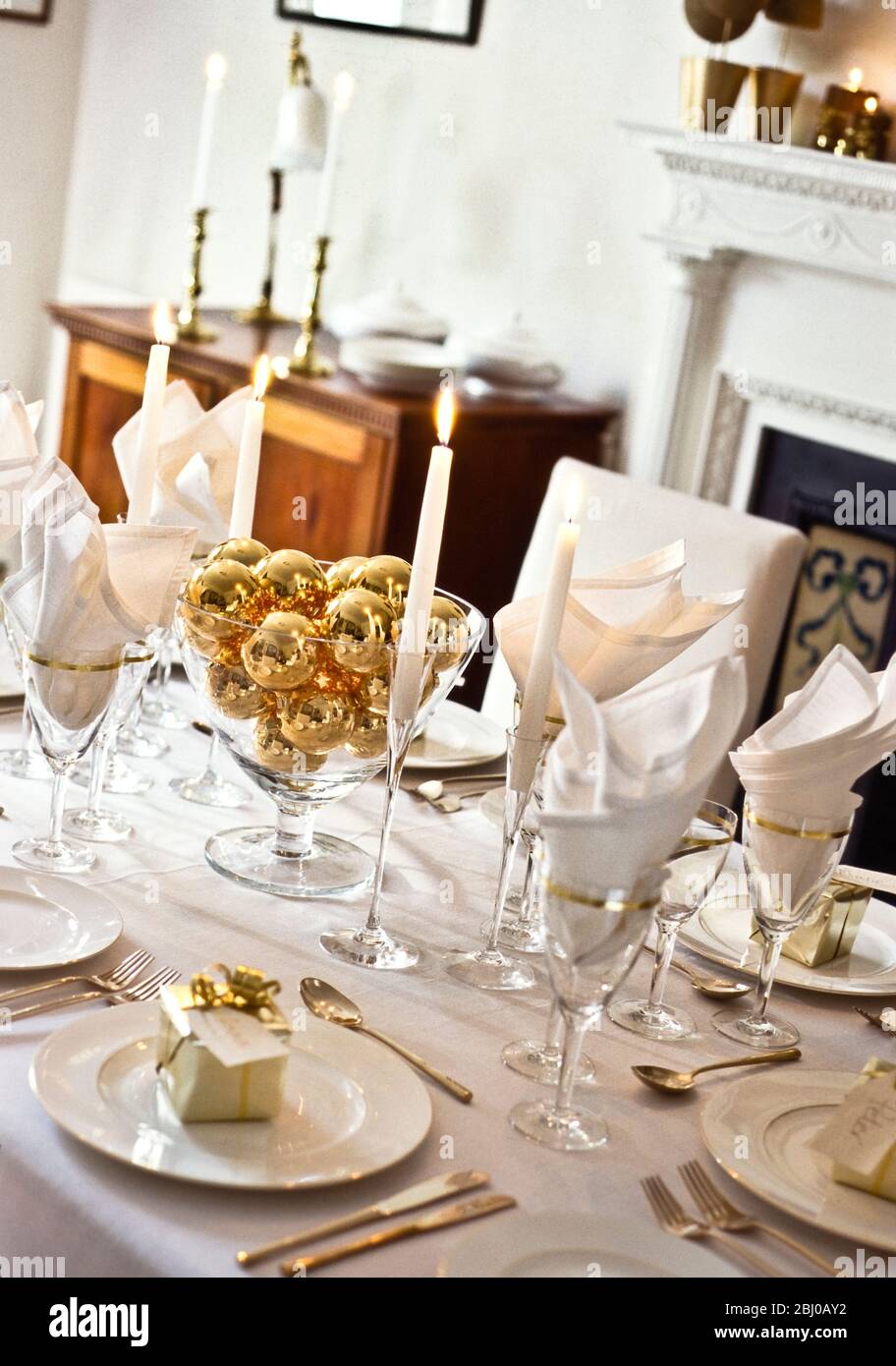 Table laid for Chritmas or a special occasion such as a Golden wedding party in elegant white dining room - Stock Photo