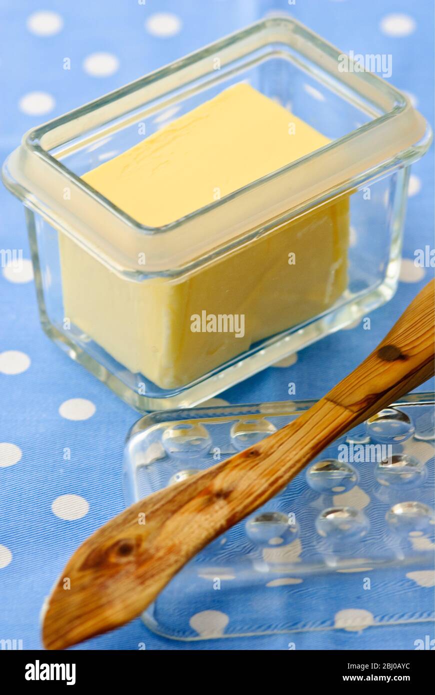 Glass butter dish of butter with butter knife on blue and white spotted