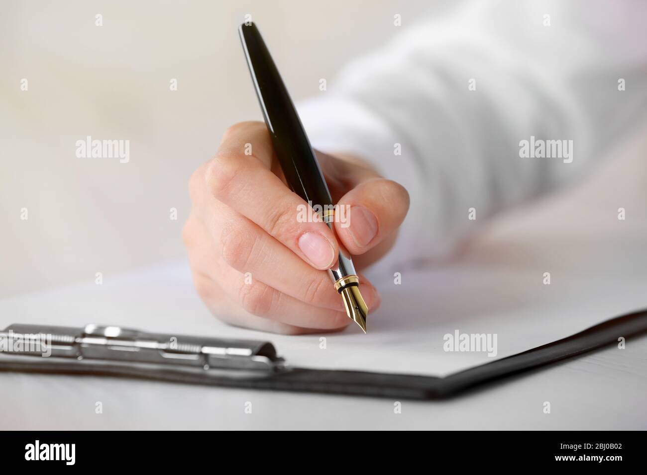 Female hand with pen writing on paper at workplace Stock Photo - Alamy