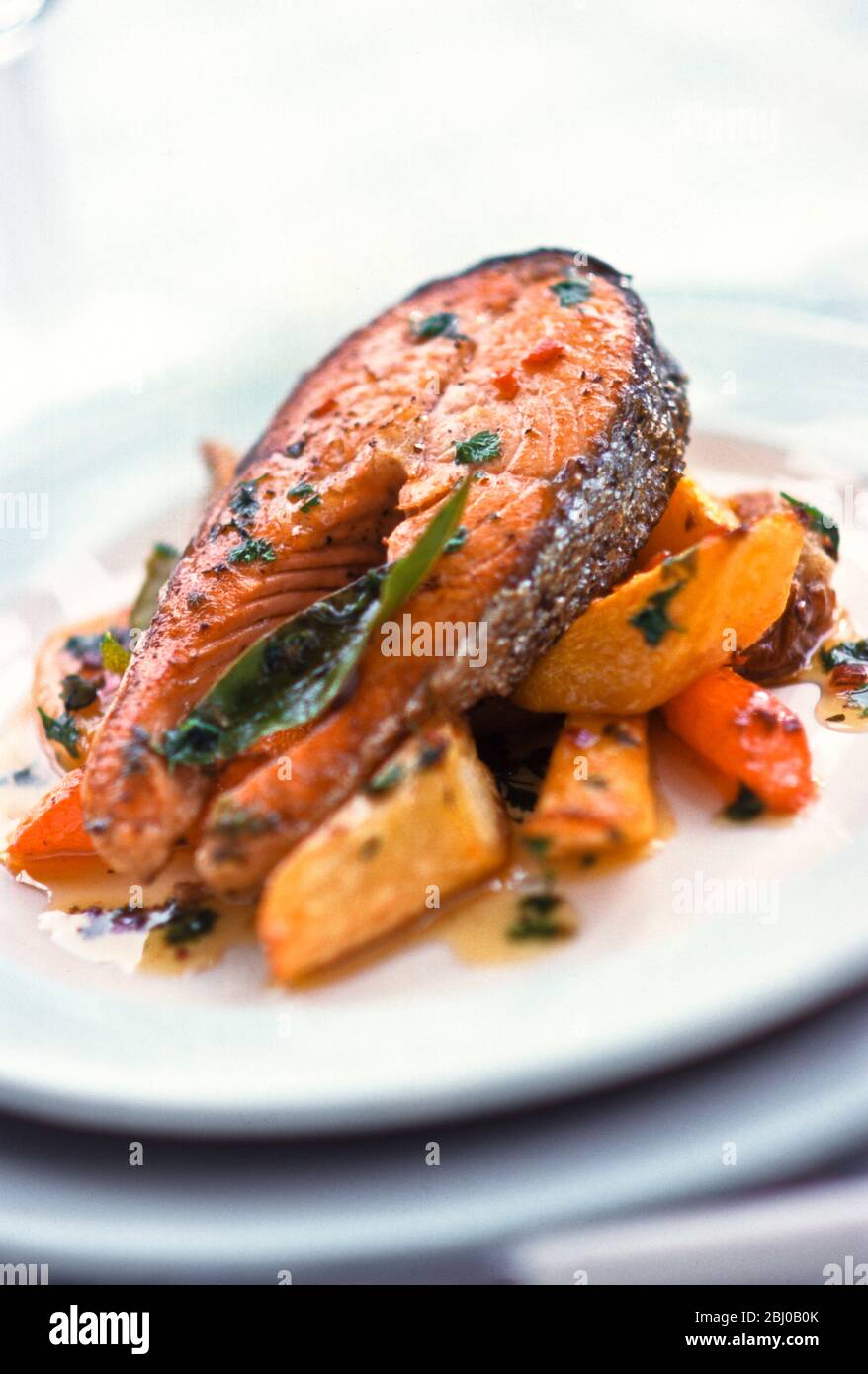 Grilled salmon steak on mixed roast root vegetables - Stock Photo