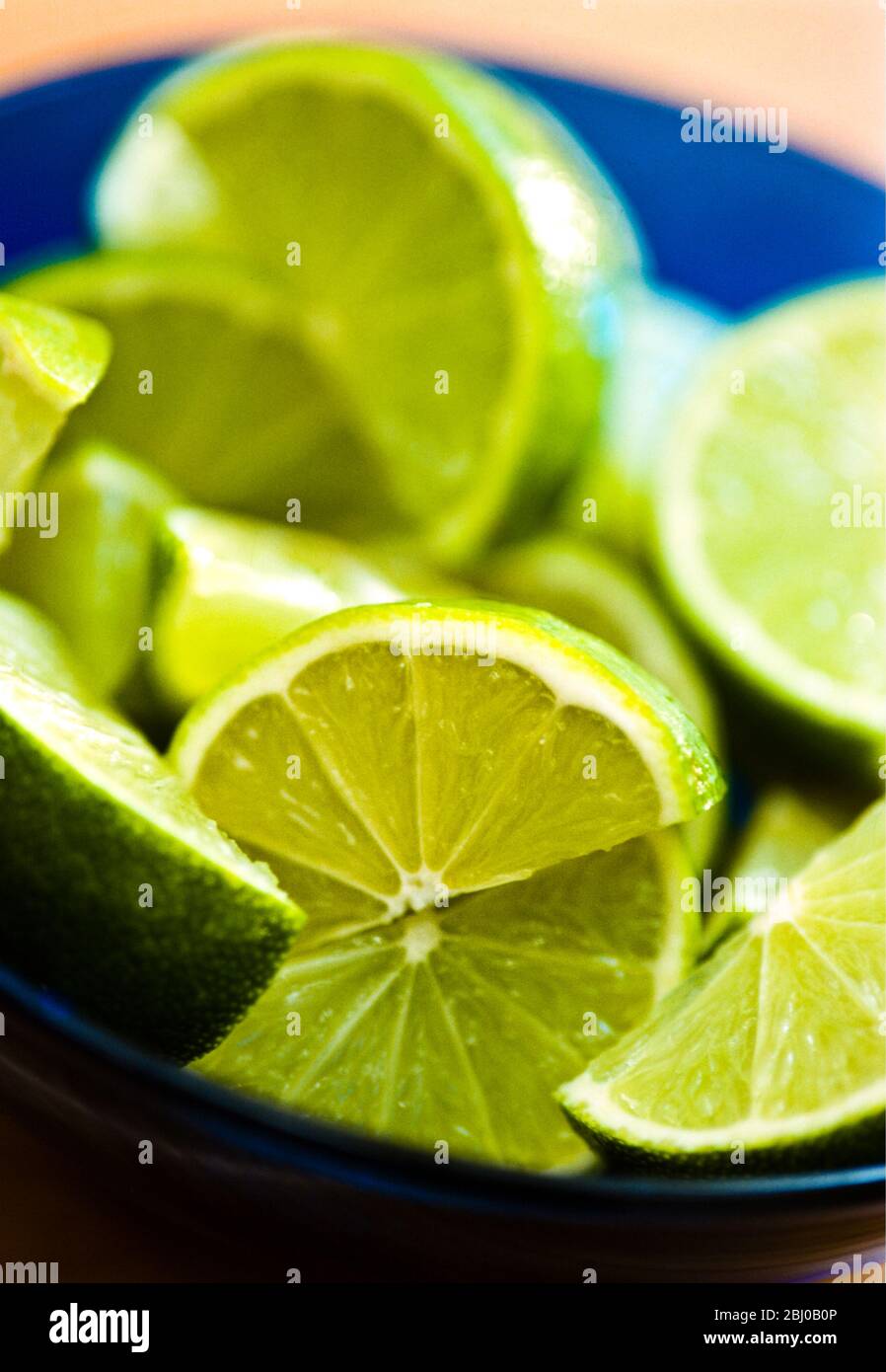 Fresh cut limes in blue bowl - Stock Photo