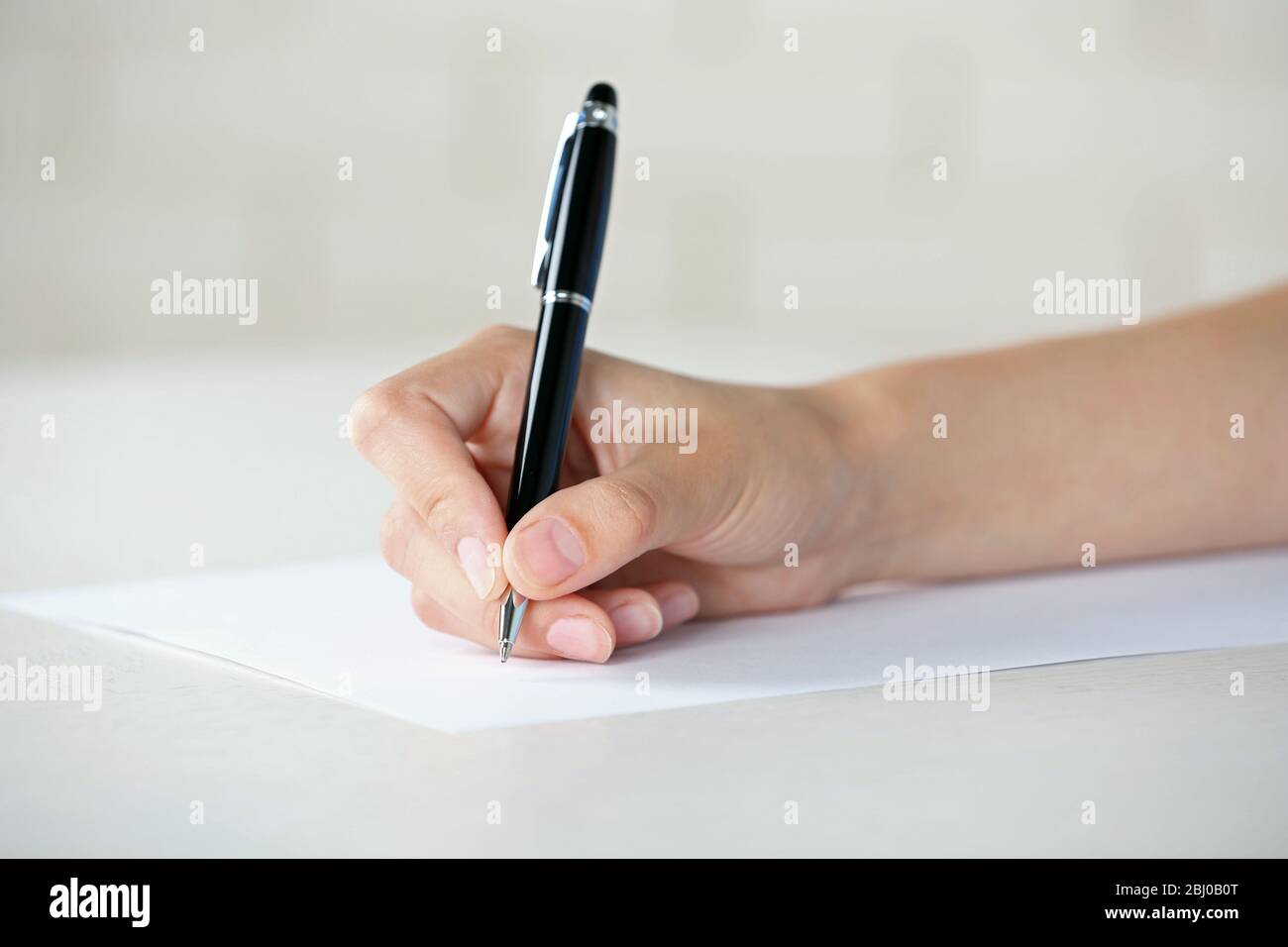 Female hand with pen writing on paper at workplace Stock Photo - Alamy