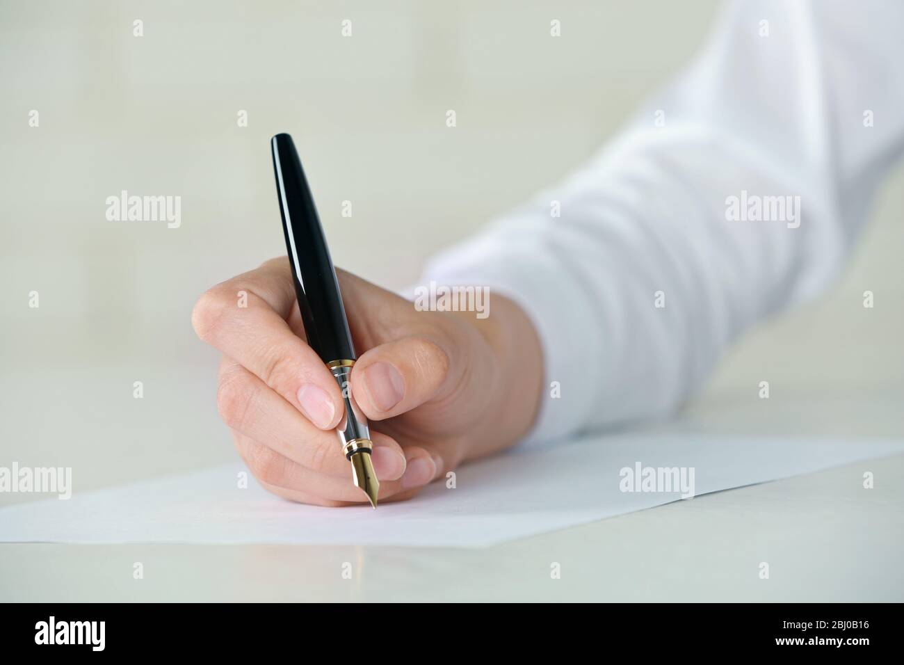 Female hand with pen writing on paper at workplace Stock Photo - Alamy