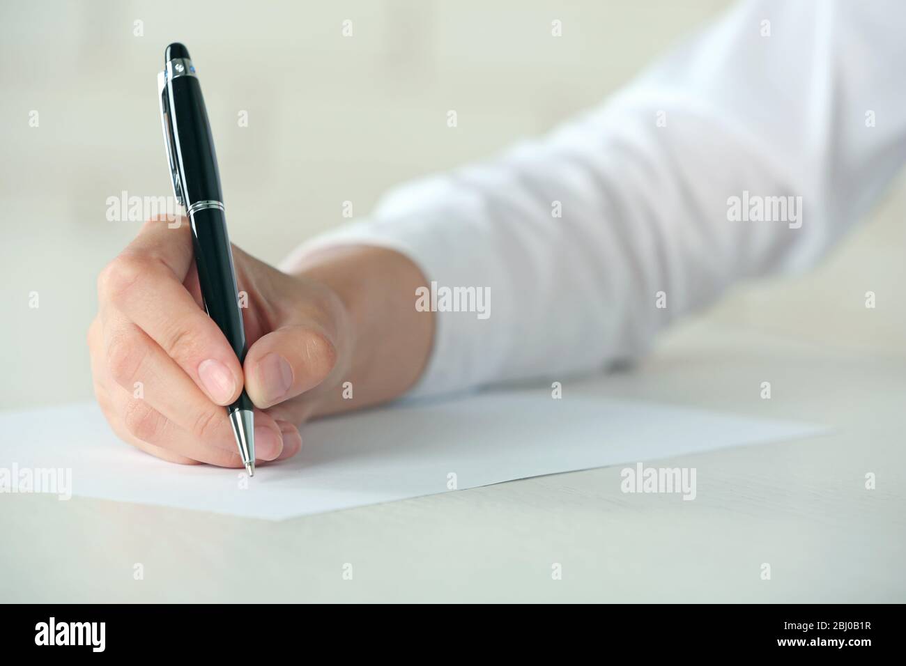 Female hand with pen writing on paper at workplace Stock Photo - Alamy