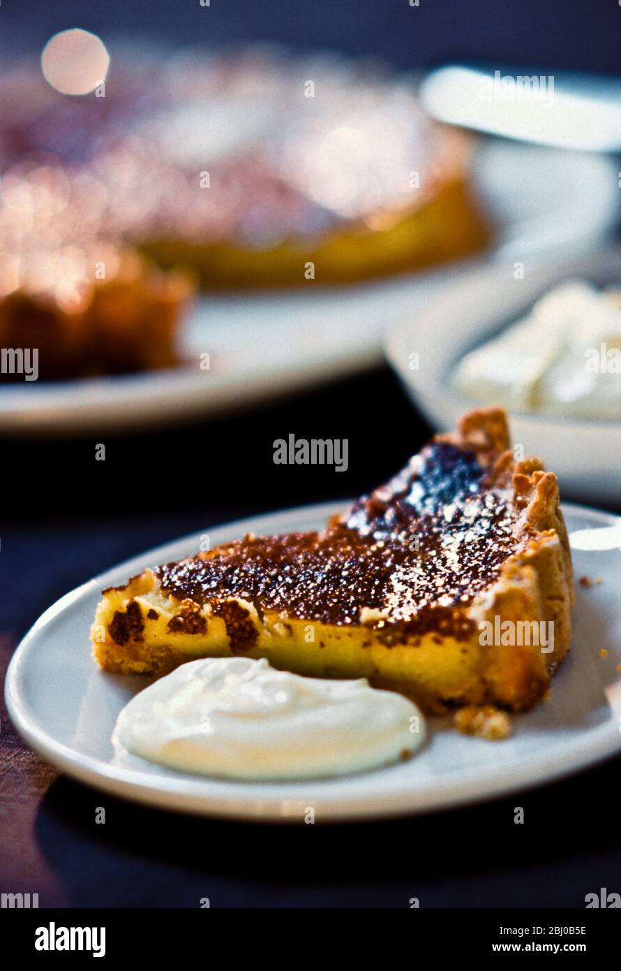Slice of lemon tart with caramelised top, served with creme fraiche - Stock Photo