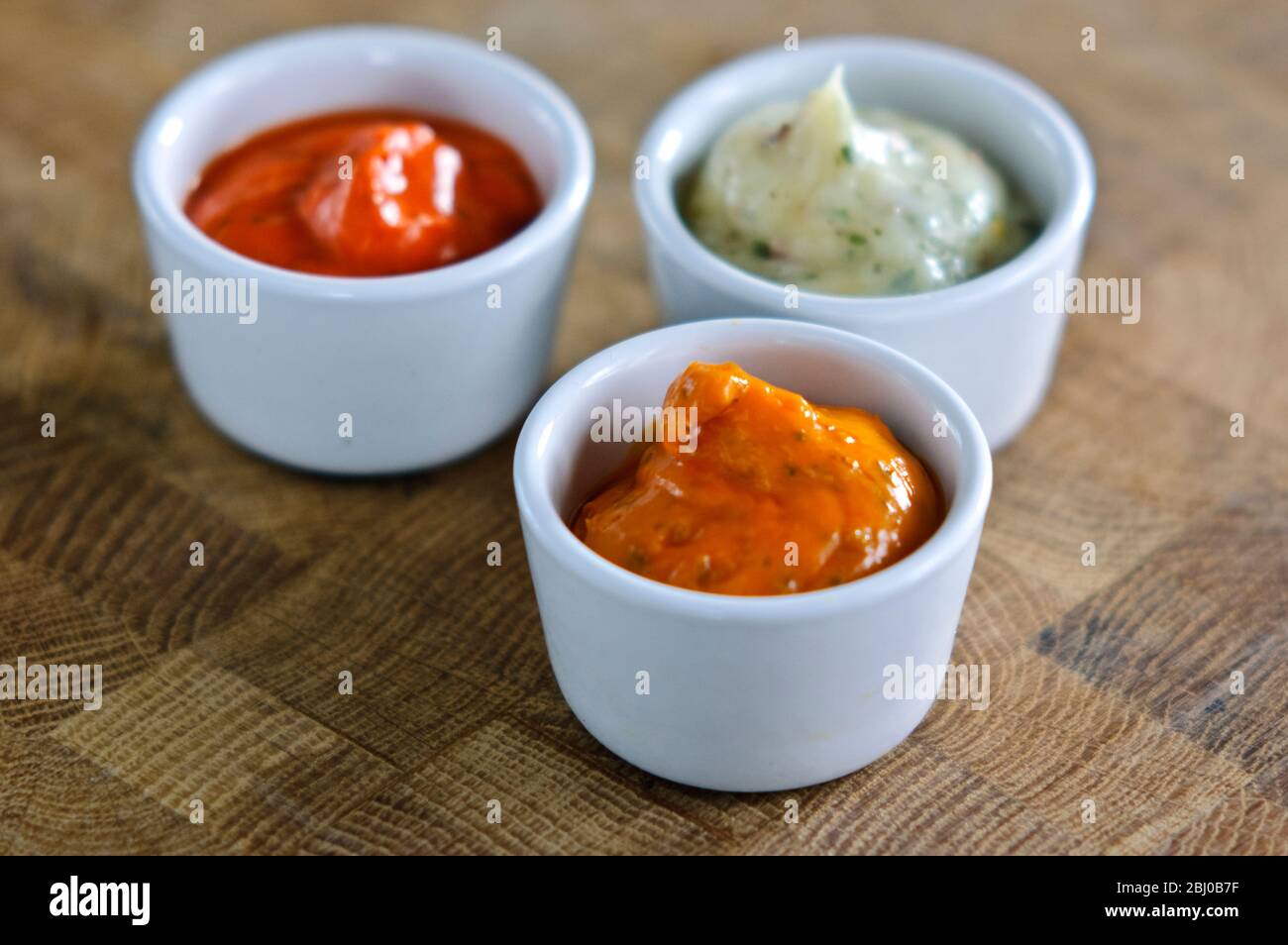 Small pots of commercial sauces used for glazing meaat before grilling. Also can be used as relish - Stock Photo