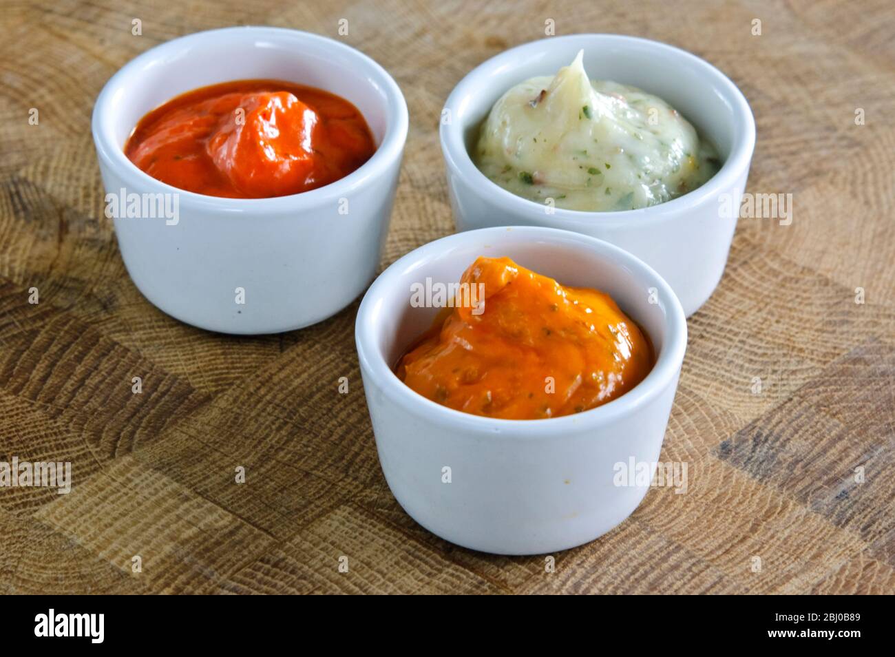 Small pots of commercial sauces used for glazing meaat before grilling. Also can be used as relish - Stock Photo