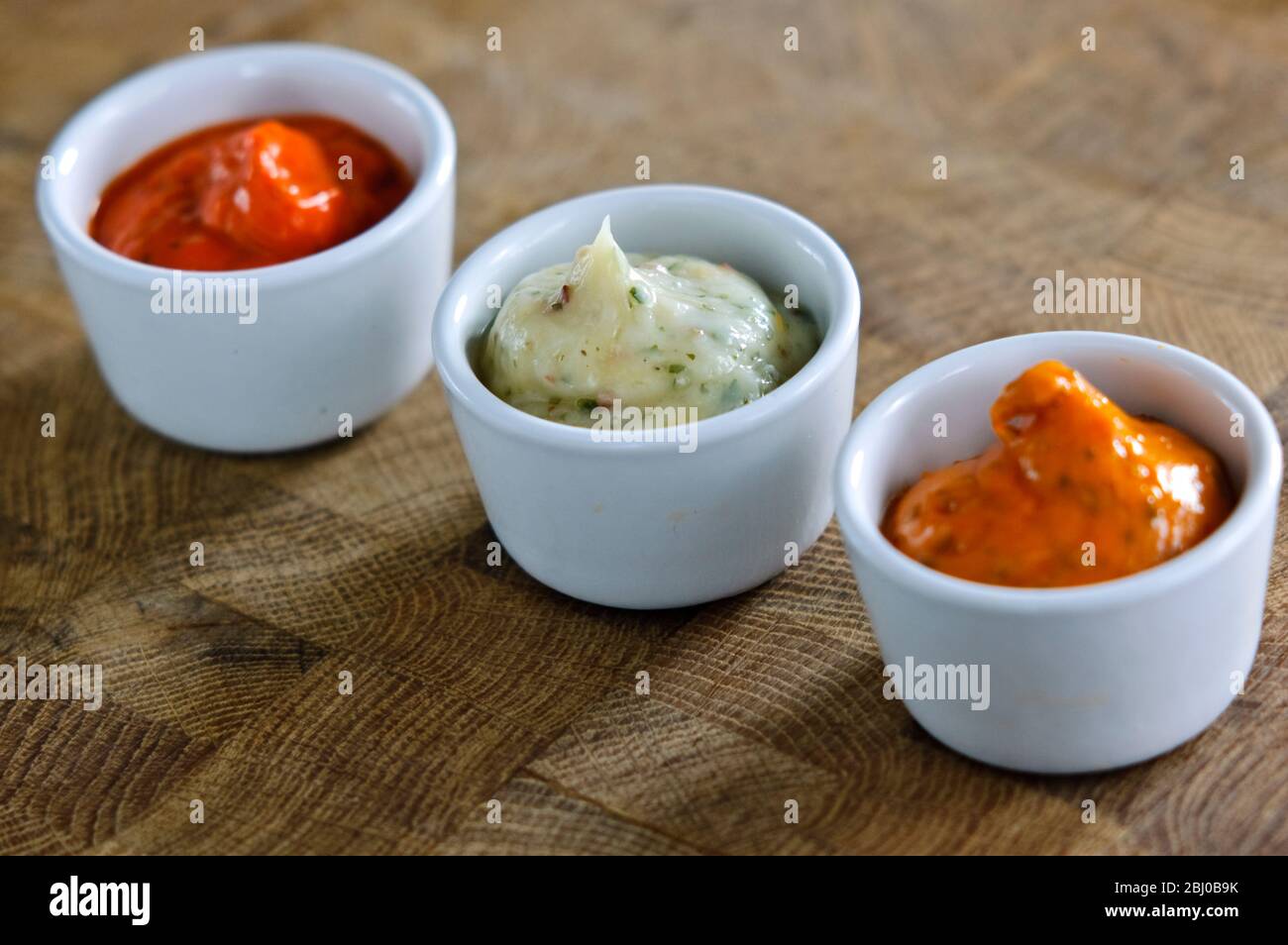 Small pots of commercial sauces used for glazing meaat before grilling. Also can be used as relish - Stock Photo