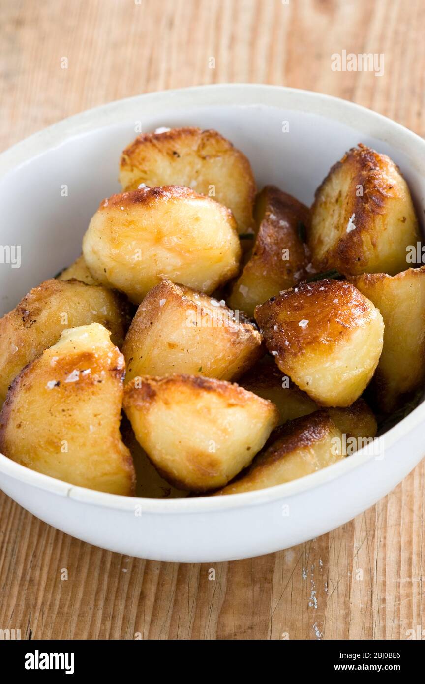 White china bowl of roast potatoes - Stock Photo