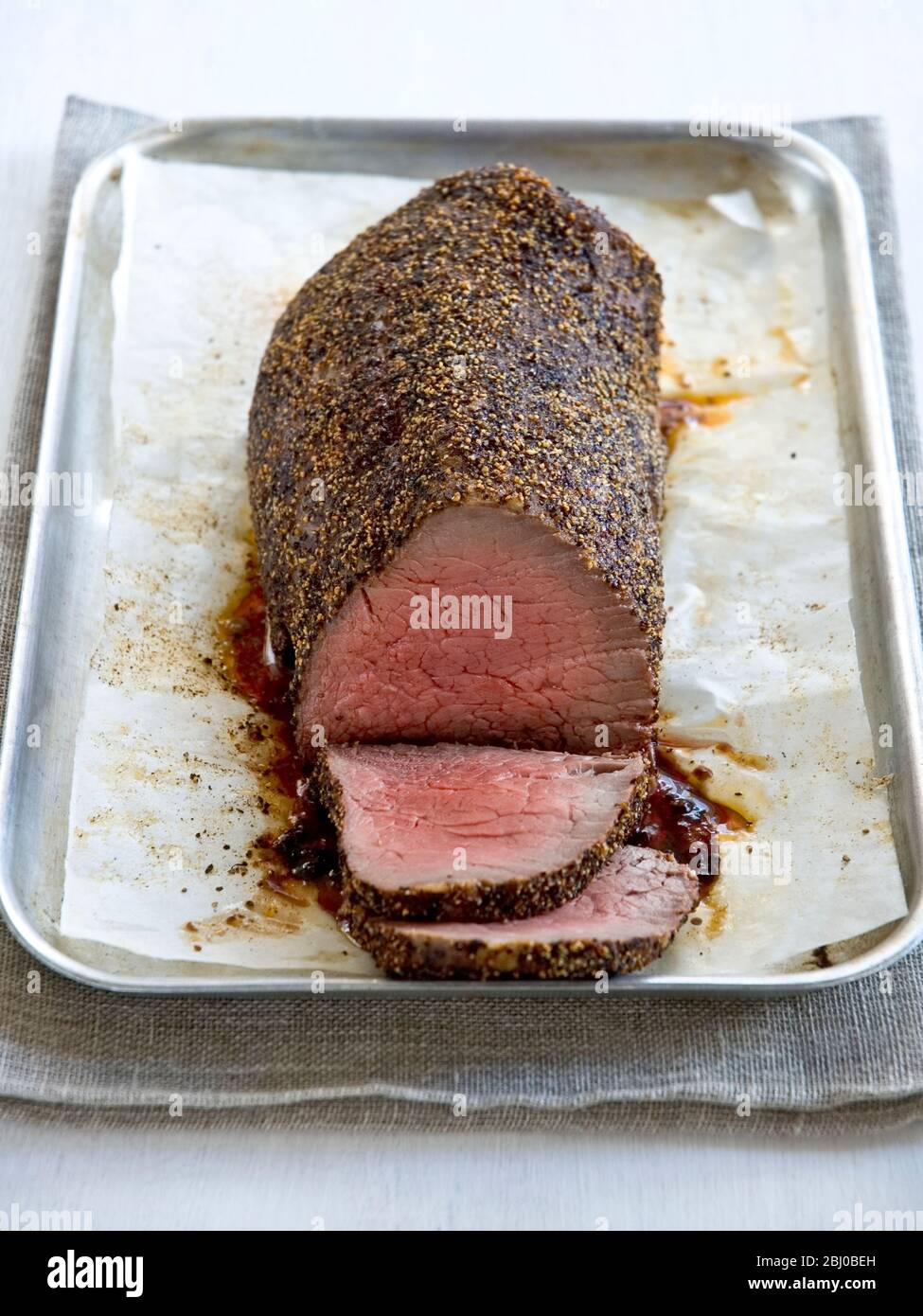 Roast fillet of beef with pepper coating in roasting tin - Stock Photo